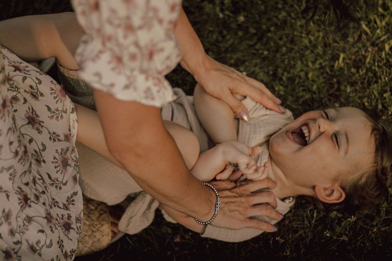 Family members relaxing together on grass during outdoor photography session.