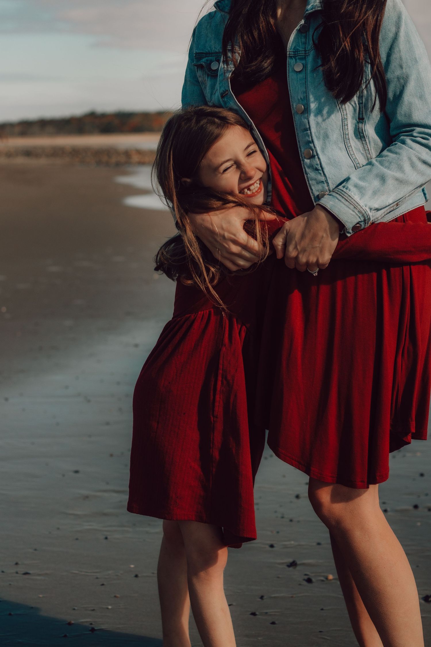 Playful beach scene with denim jacket and flowing red skirt against ocean backdrop.