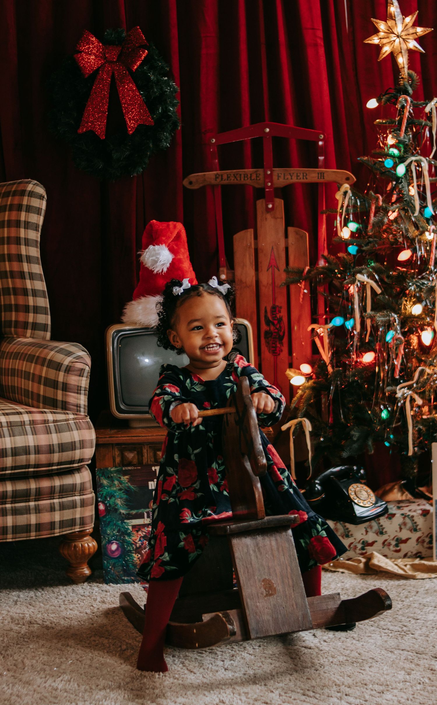 Child plays joyfully by a decorated Christmas tree with vintage decor and plaid furniture.