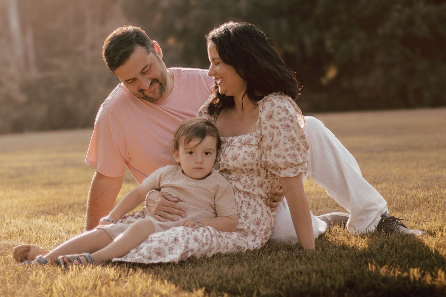 Family lying together on grass during golden hour sunset photoshoot.