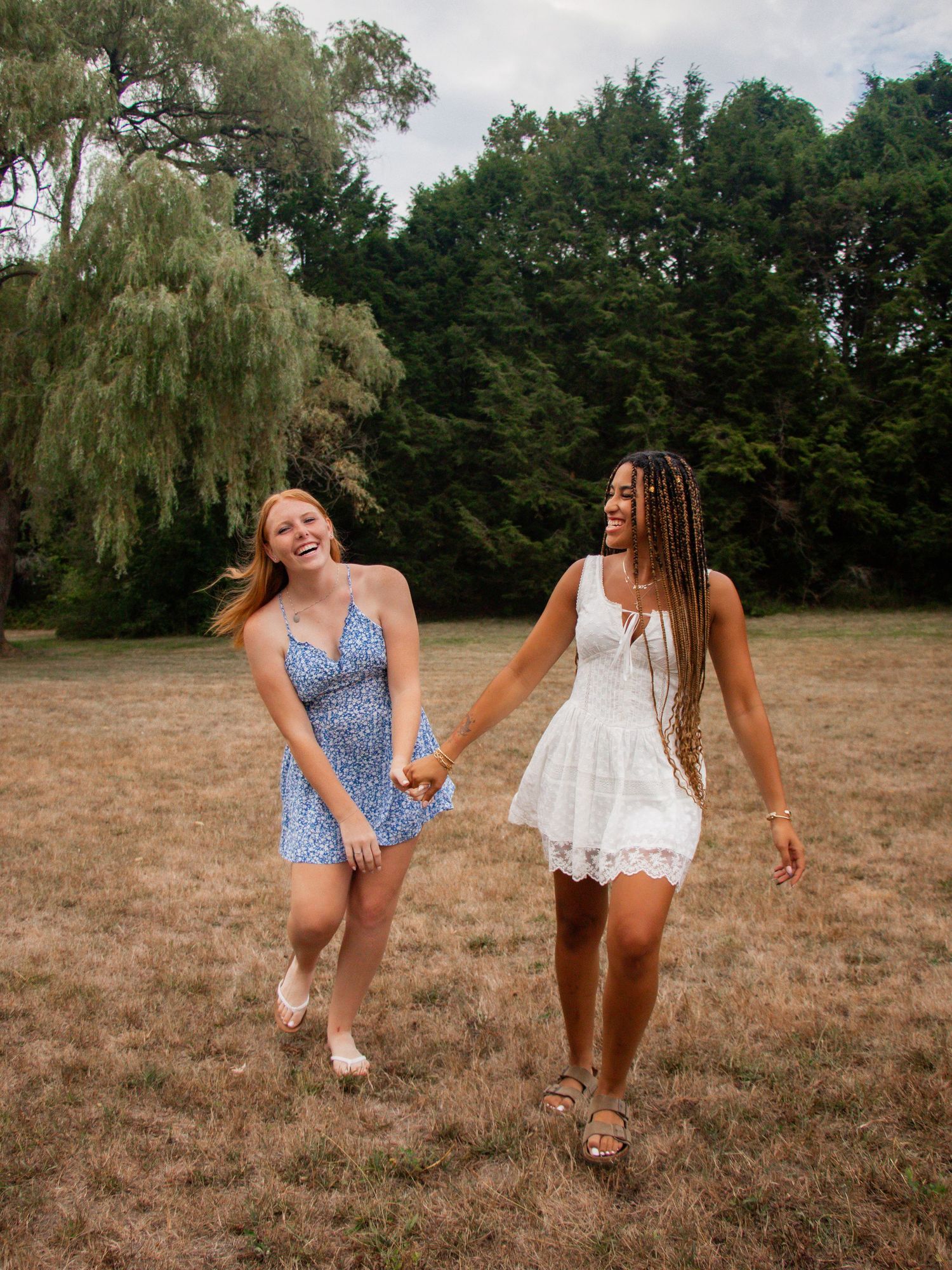 Friends in swimsuits dancing and laughing together in a sunny field.
