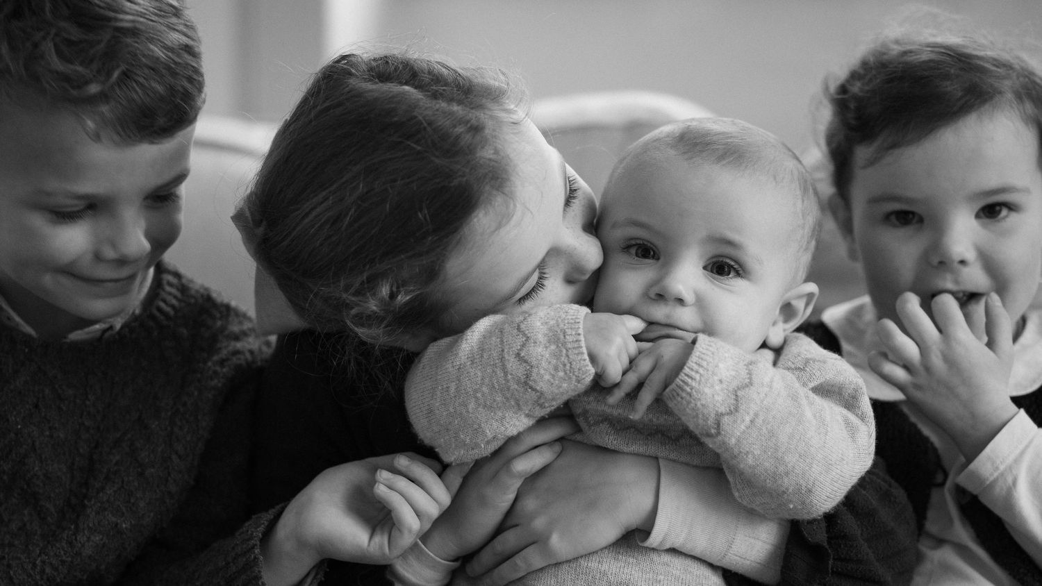 Black and white photographs showing tender moments between brothers and sisters.
Portrait de famille en noir et blanc de 4 enfants.