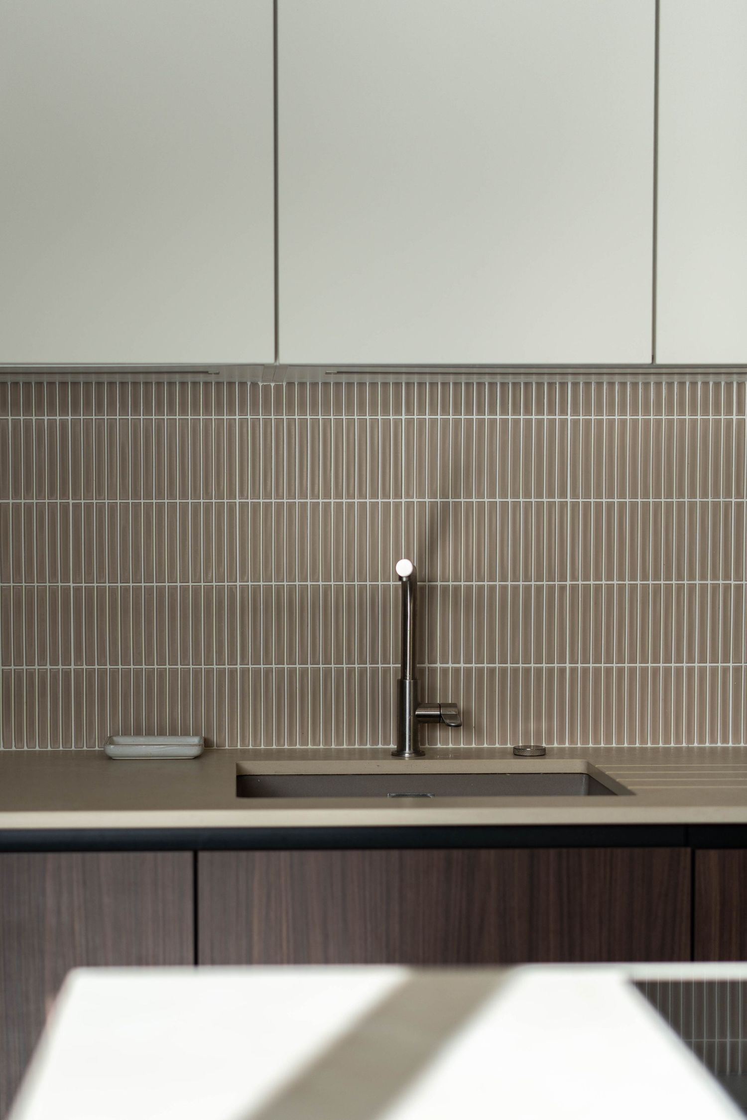 Sleek modern kitchen sink with black faucet against vertical tile backsplash.
Robinetterie cuisine moderne