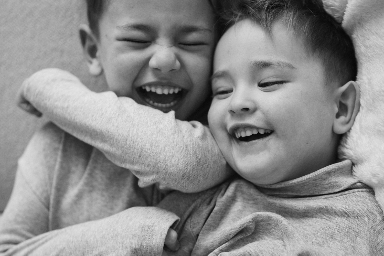 Black and white photographs capturing joyful interactions between brothers.
Deux petits garçons chahutant et riant sur le canapé.