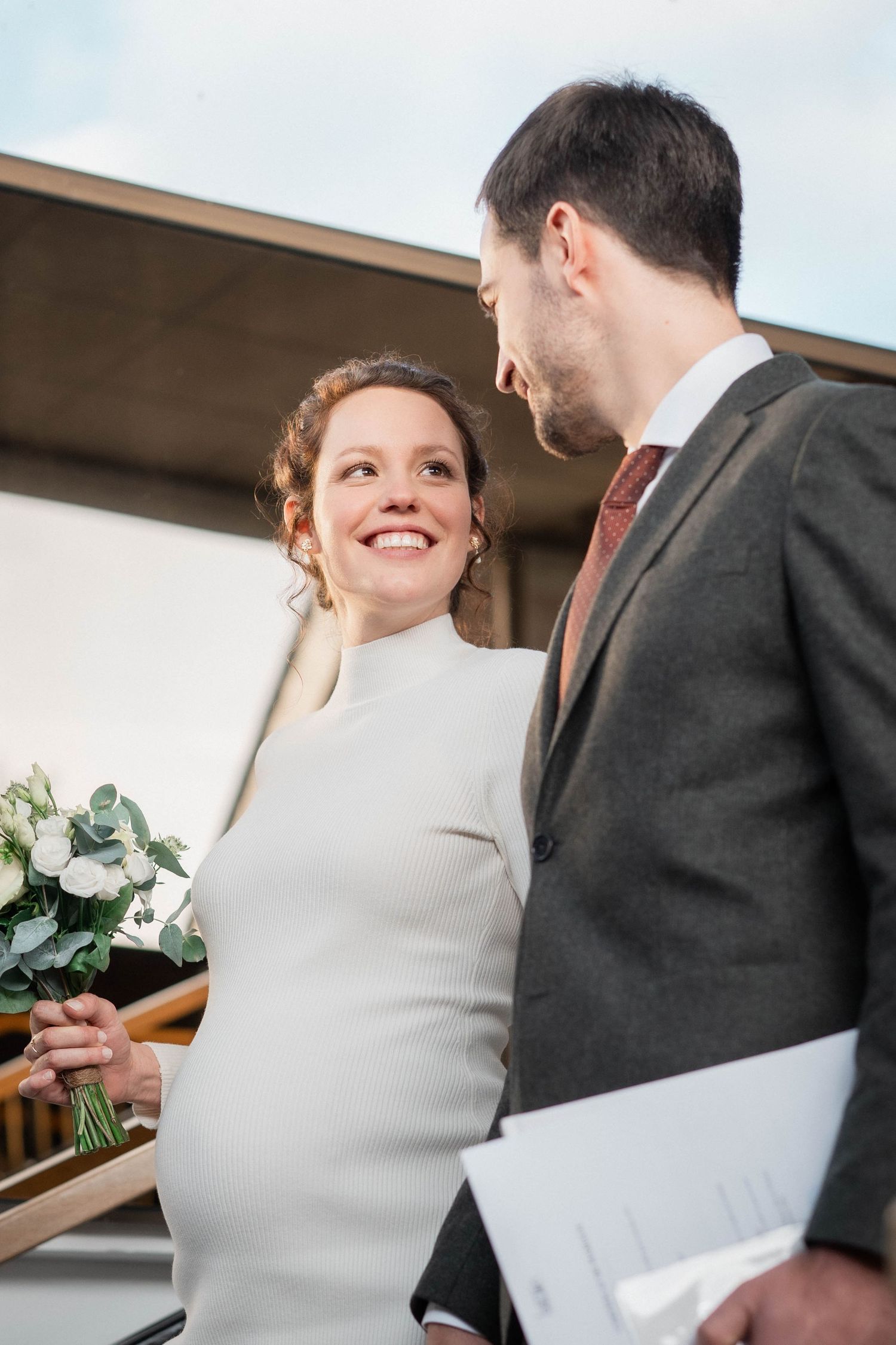 Elegant couple in wedding attire sharing joyful moment with white bouquet.
Mariés souriant et se regardant tendrement.