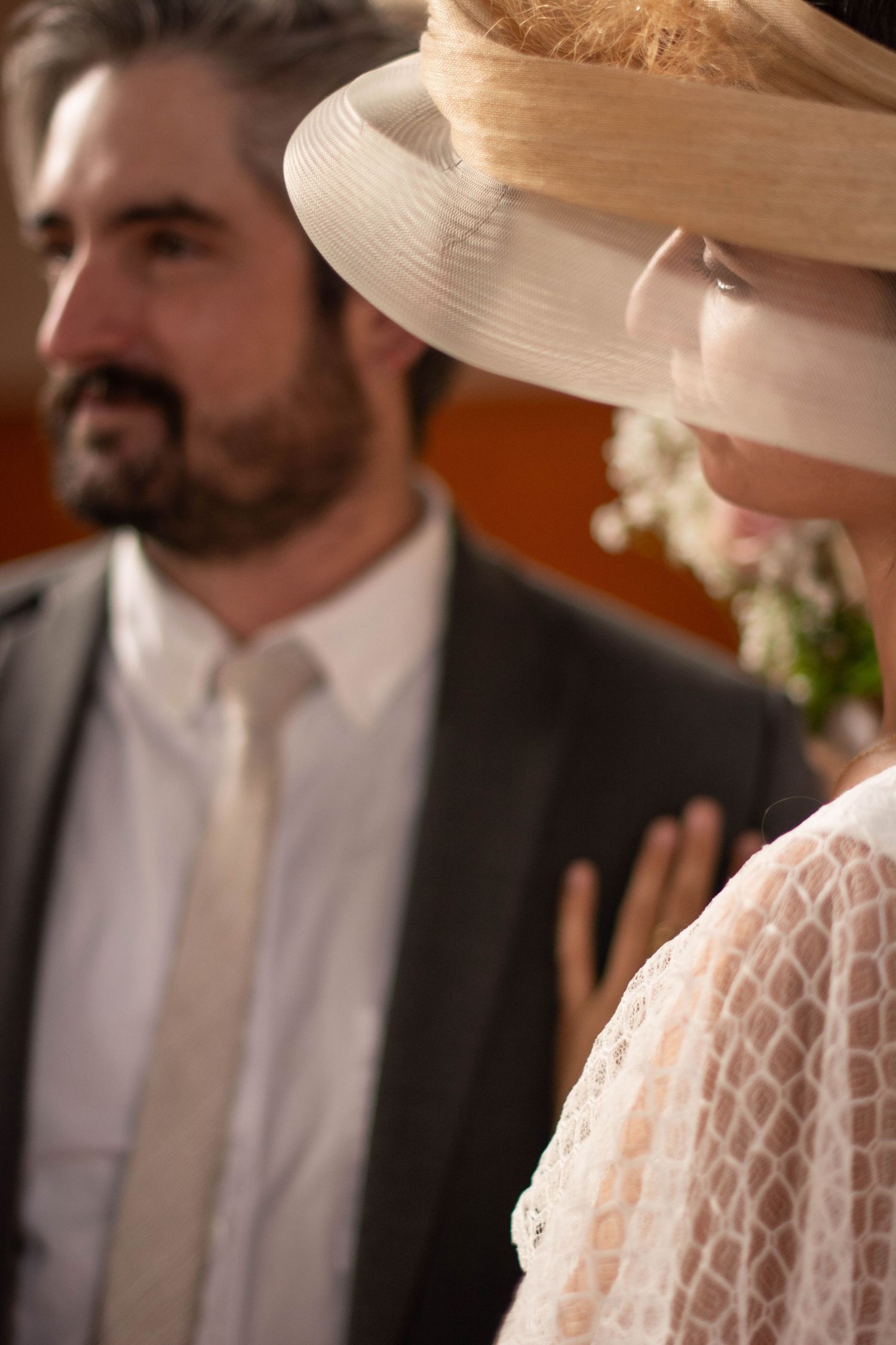Side view of wedding attendees with the bride wearing a dramatic wide-brimmed hat.