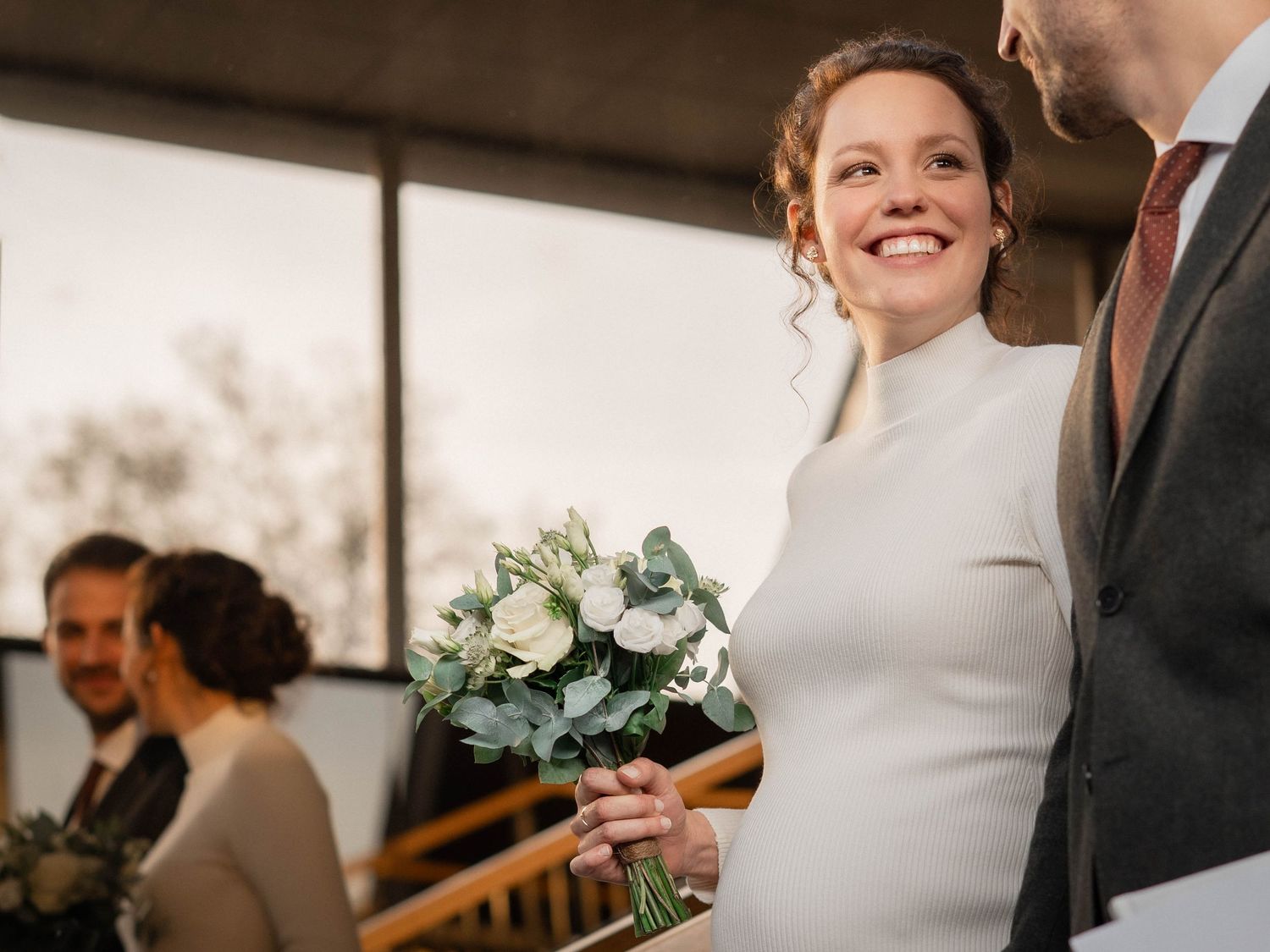Indoor wedding celebration with elegant white dress and floral arrangements.
Photographie d'une mariée souriante et tenant son bouquet