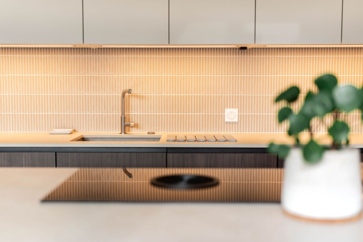 Contemporary kitchen with peach-toned backsplash, brass faucet, and wooden countertop.