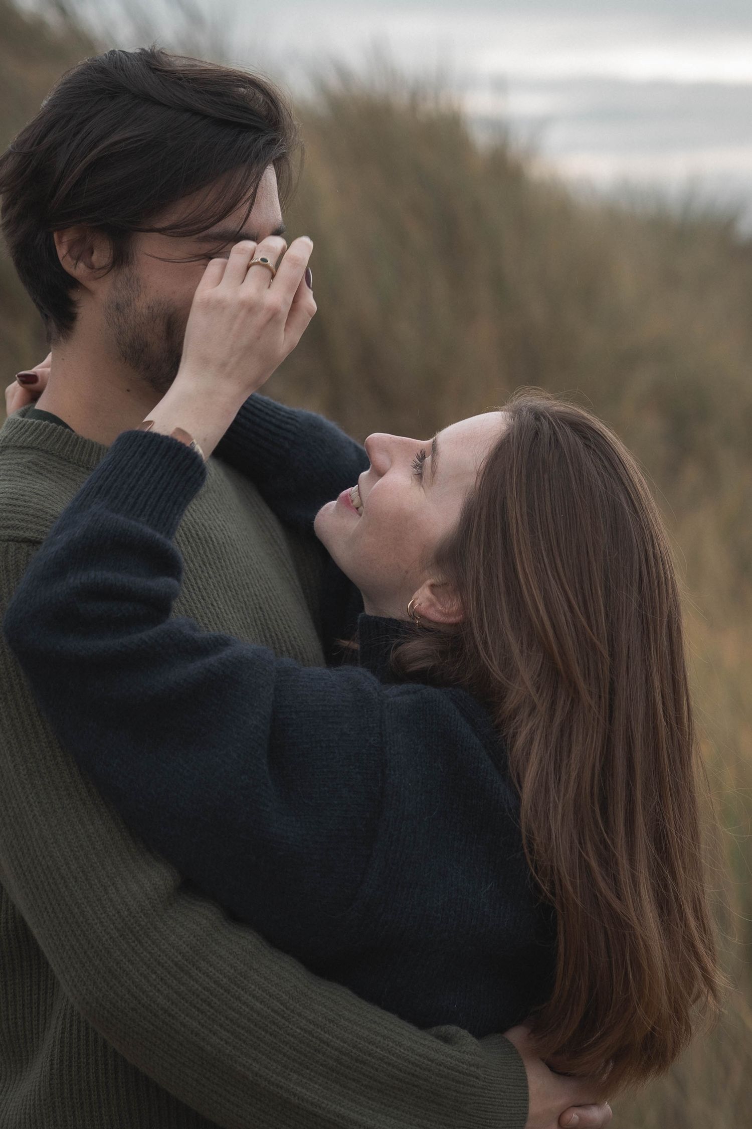 Couple looking up at the sky through their hands in tall grass by the coast.
Couple s’enlaçant dans les hautes herbes.