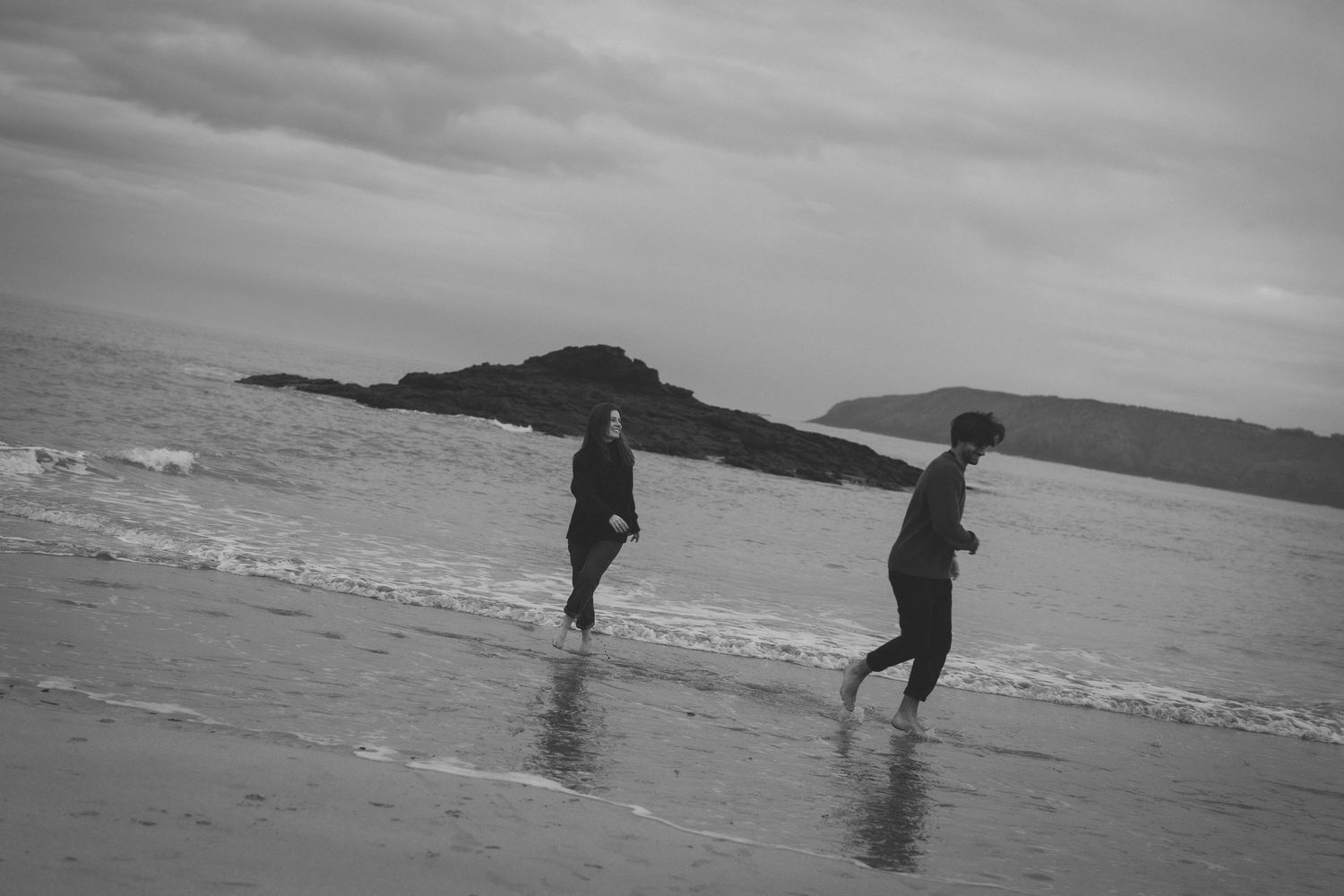 Silhouettes walking and playing along a dramatic coastal shoreline.
Photo noir et blanc d'un couple jouant. effet flou.
