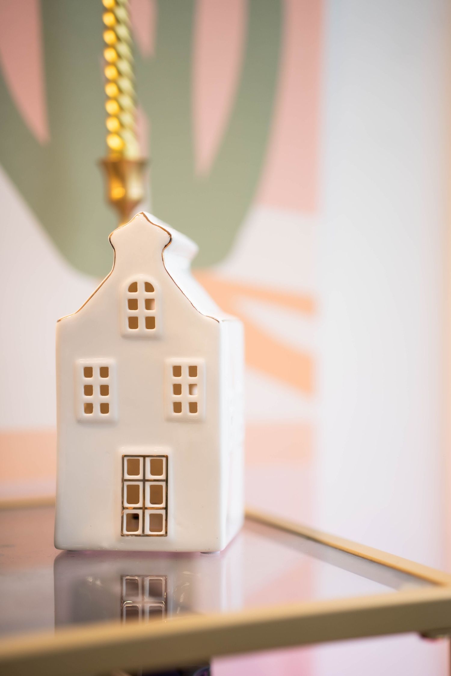 Small decorative white ceramic house with glowing windows on a pastel background.
Maison style nordique en céramique décorative