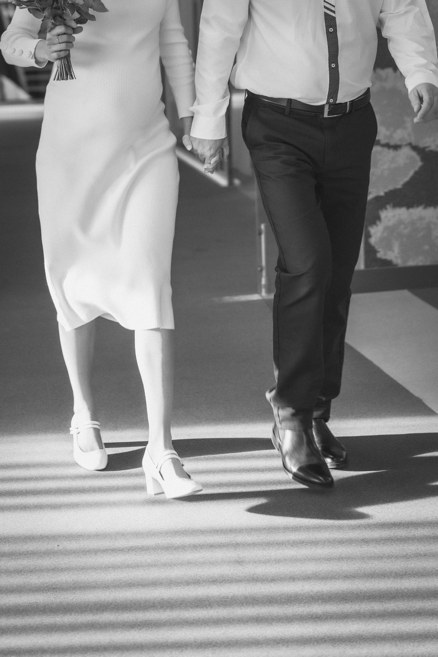 Black and white image of wedding guests' feet walking in formal shoes.