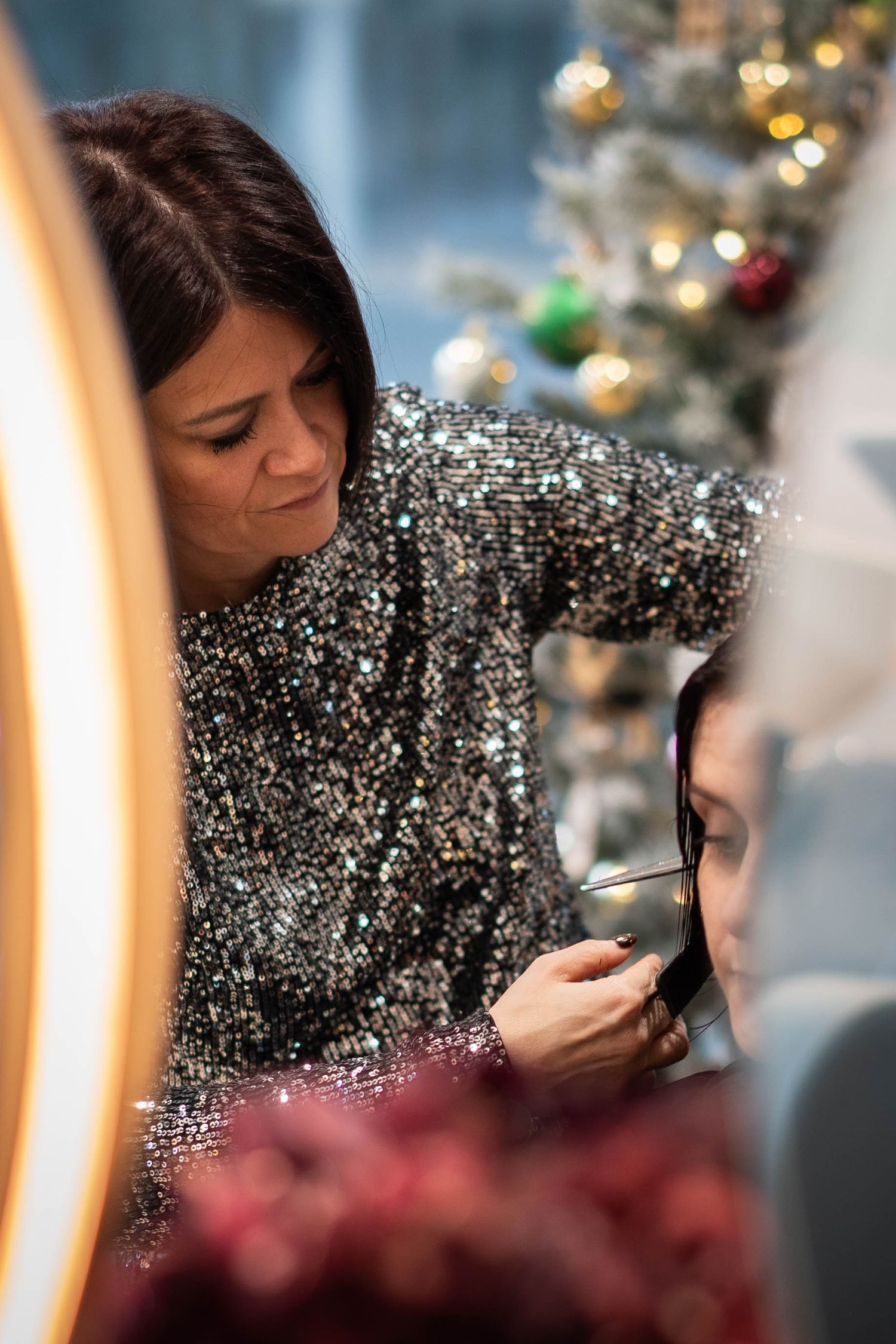 Makeup artist in sparkly sequined dress working on a client during a holiday season photoshoot.
Coiffeuse travaillant pendant Noël