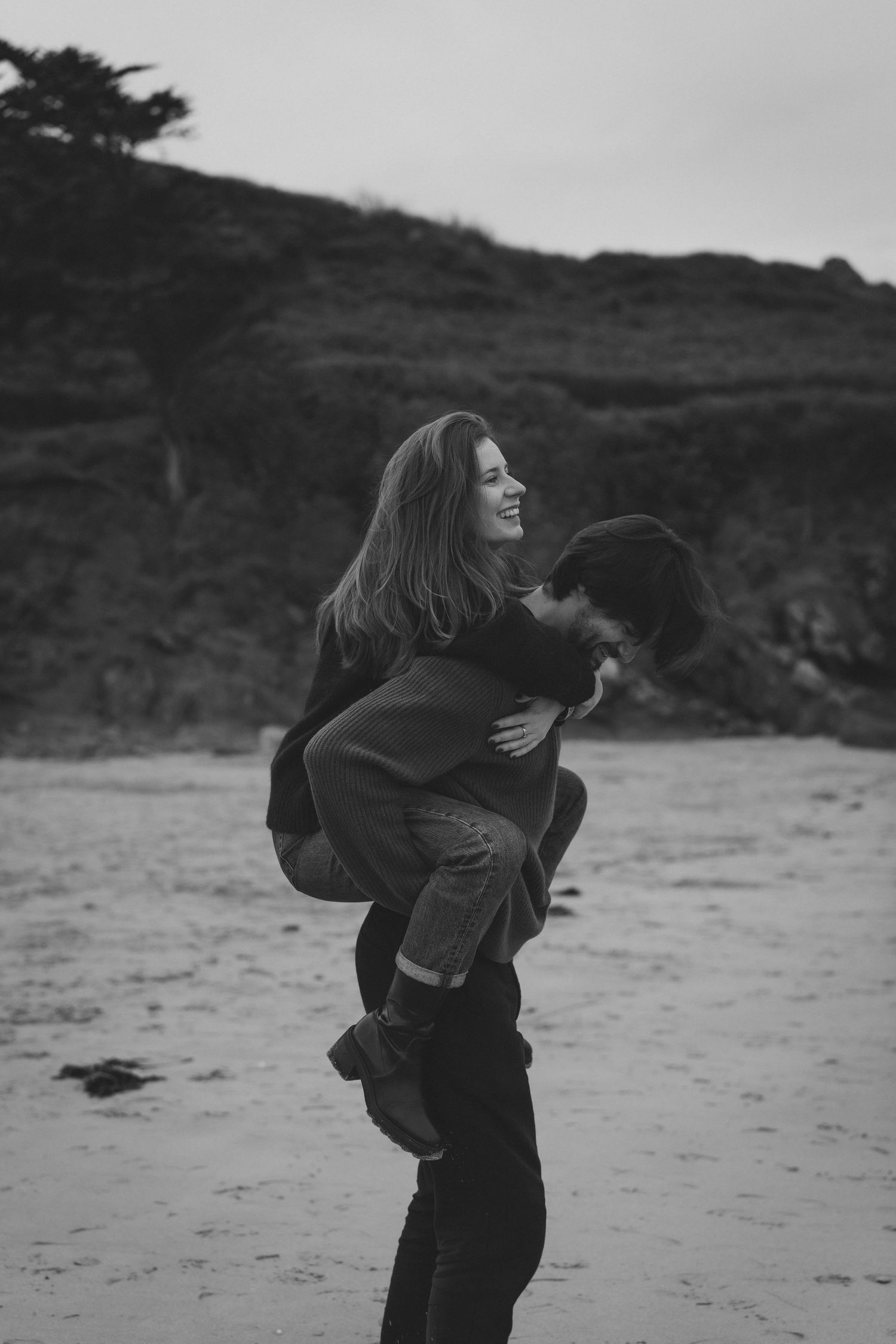 Black and white photo of two people hugging and laughing together on a beach.
Photo de couple sur la plage s'amusant en noir et blanc.