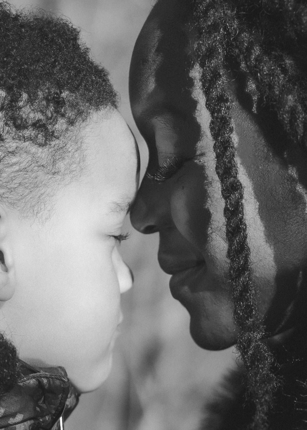 An intimate black and white close-up portrait showing a tender moment between parent and child.
Photo noir et blanc d'une mère et son fils.