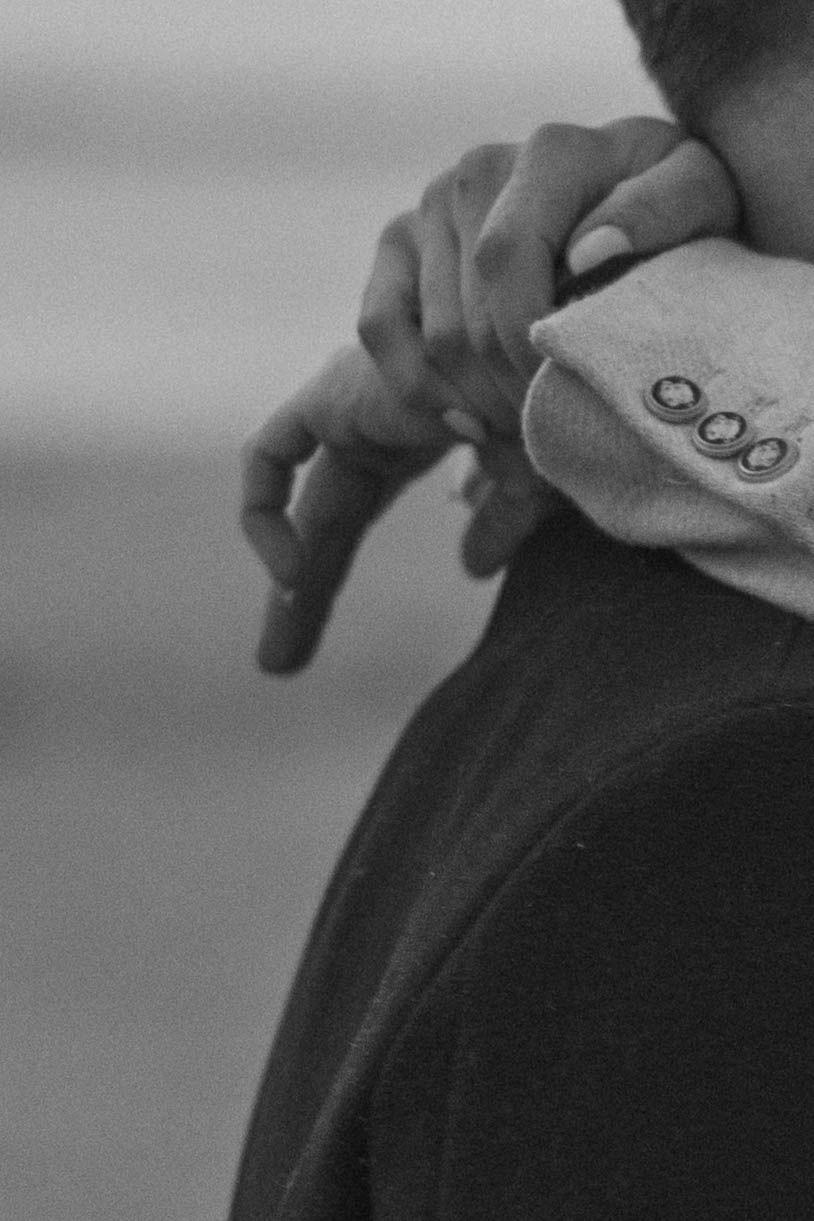 Close-up detail shot of fingers gently resting on dark fabric.
Couple avec mains enlacées autour du cou.