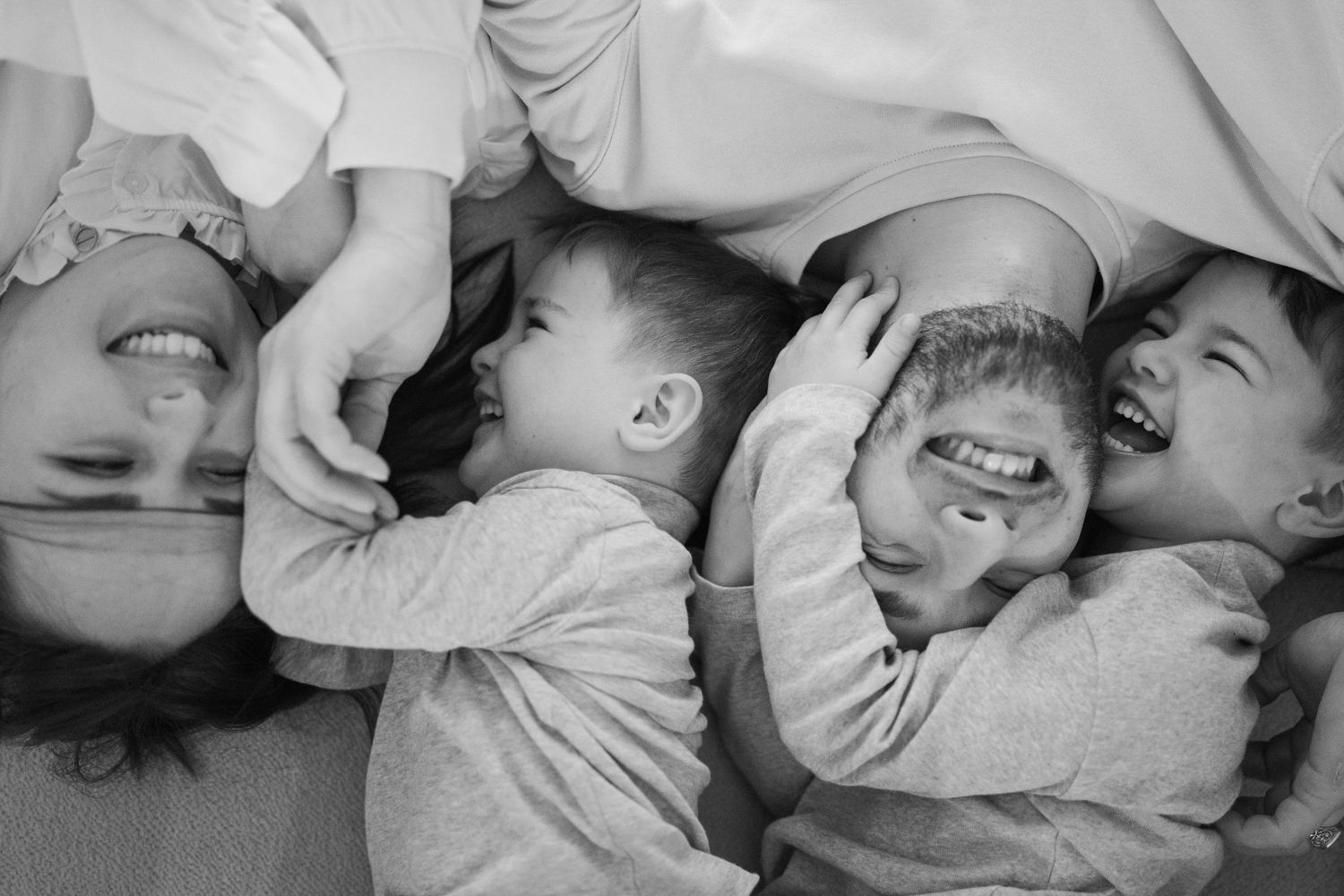 Series of black and white photographs capturing joyful moments of connection and laughter.
Deux parents et deux enfants se câlinant et riant