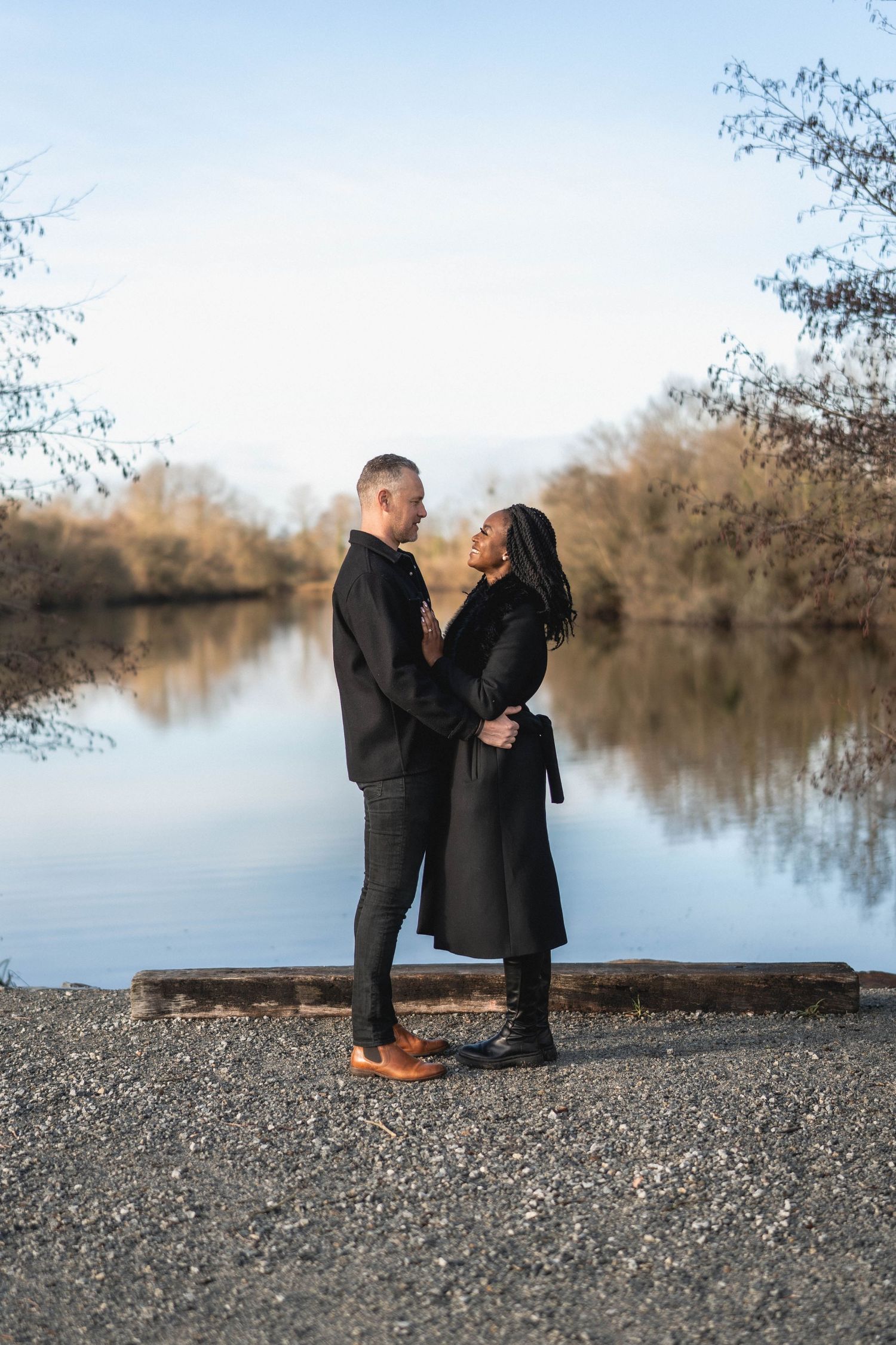 Romantic couple standing by tranquil lake during sunset with trees in background.
Couple de profil se regardant au bord d'un étang.