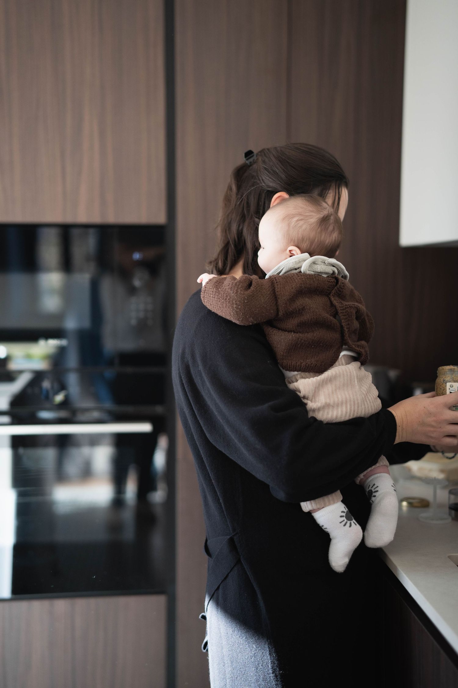 Interior shots showing intimate moments between parent and child in a modern home setting.
Maman tenant son bébé et préparant le repas.