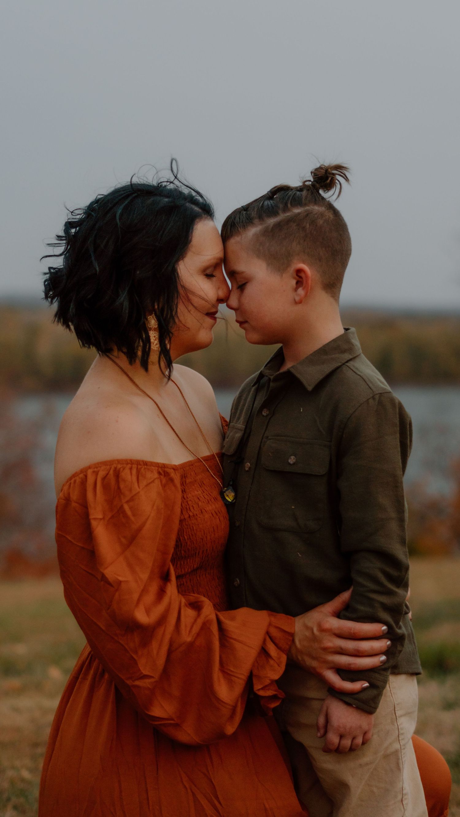 Mother and son touching foreheads in an affectionate outdoor autumn portrait.