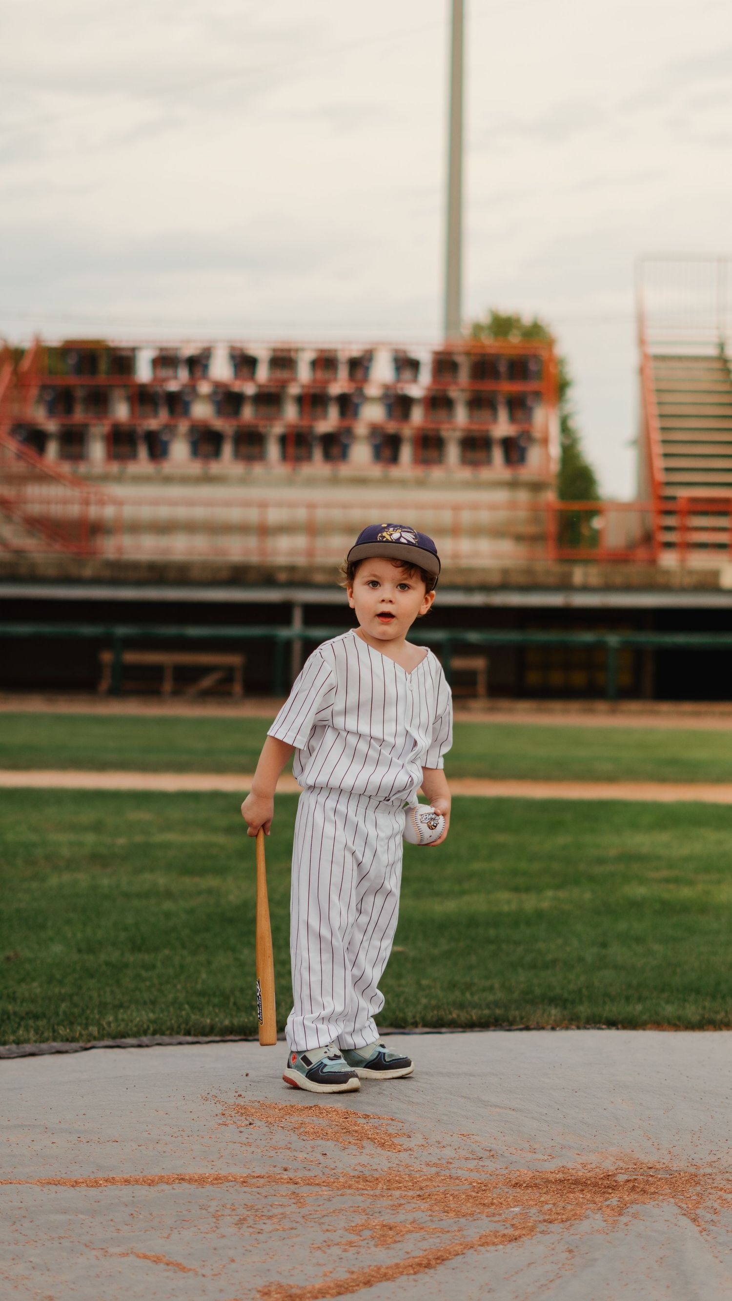 Young boy in baseball uniform holding a bat on a baseball field.
