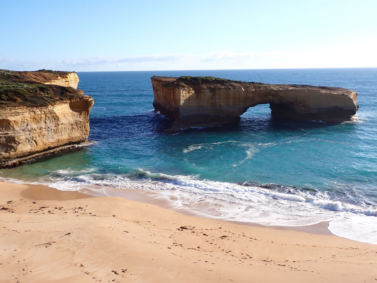 Natural rock arch formation over turquoise waters at London Bridge along the Great Ocean Road in Australia.