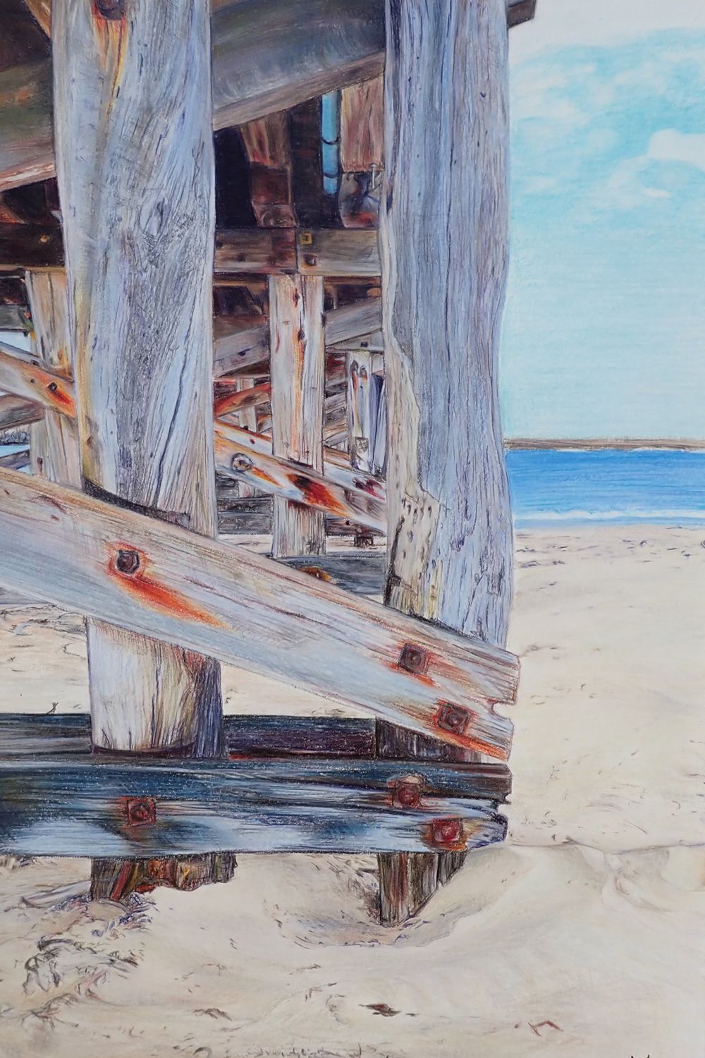 Weathered wooden pier posts stand on a sandy beach against a bright blue sky. Coffs Harbour Jetty Completed artwork by Katelizabeth.