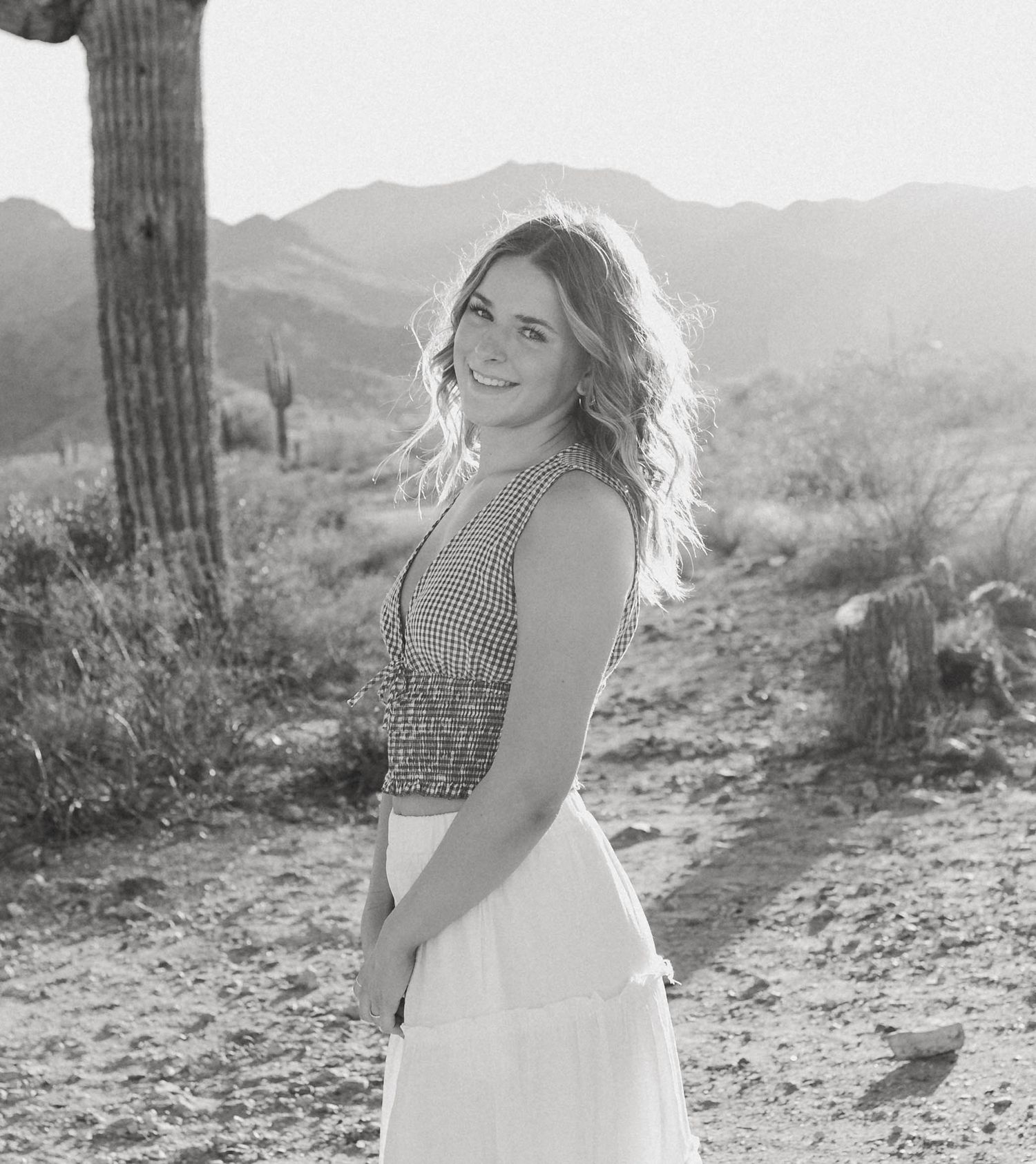 Black and white desert photoshoot featuring flowing dress and dramatic poses against saguaro cactus backdrop.