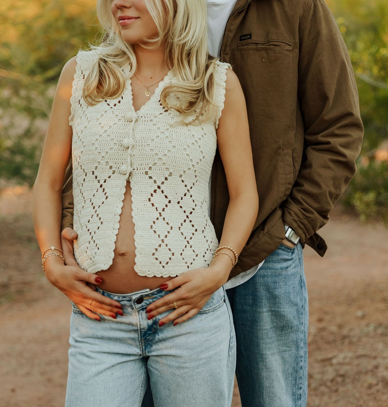 Couple in casual attire embracing outdoors with woman wearing crochet top and light denim jeans in autumn setting.