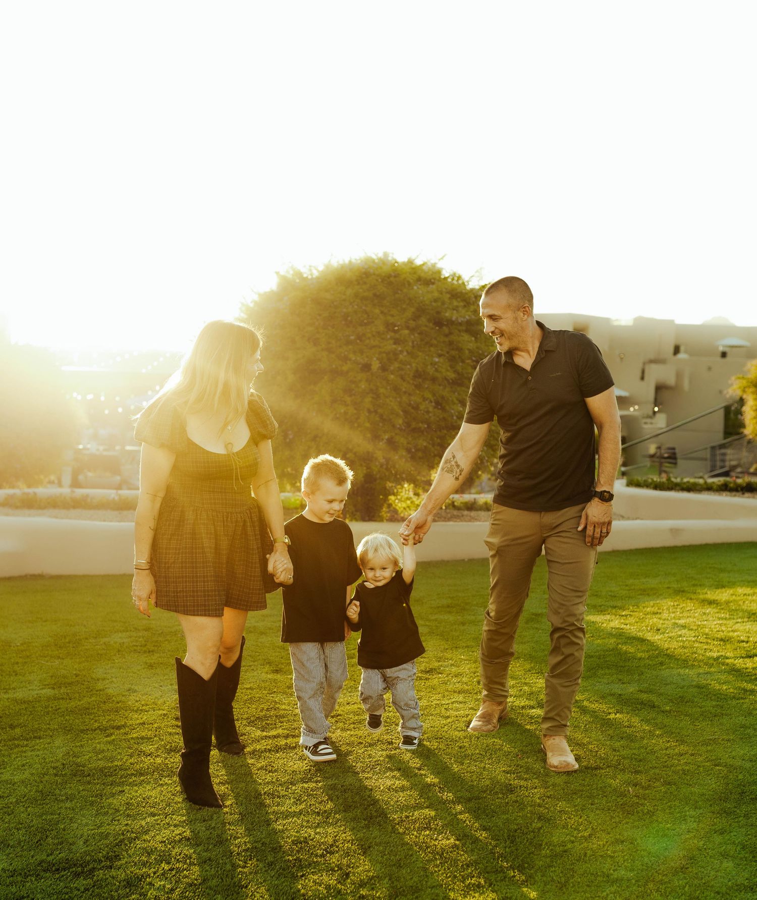 Family photos of family walking together on grass at sunset casting long shadows