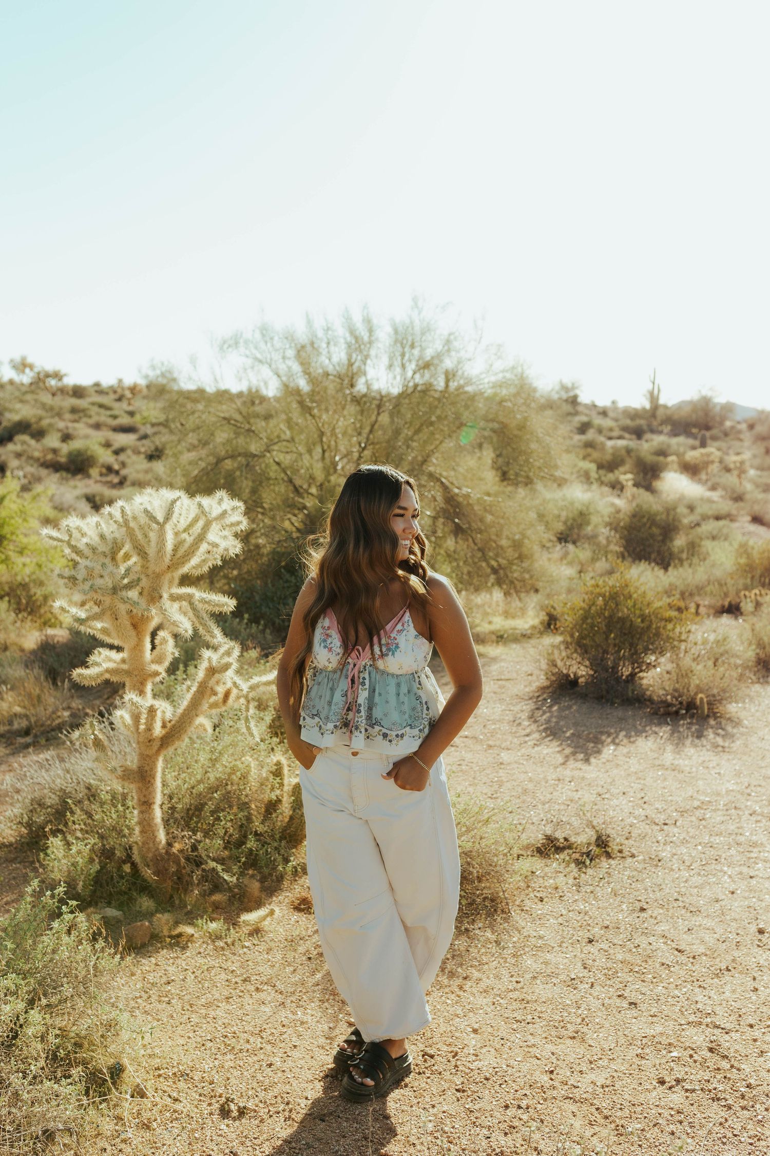 A candid Senior desert photoshoot featuring candid poses and natural desert landscape with cacti.