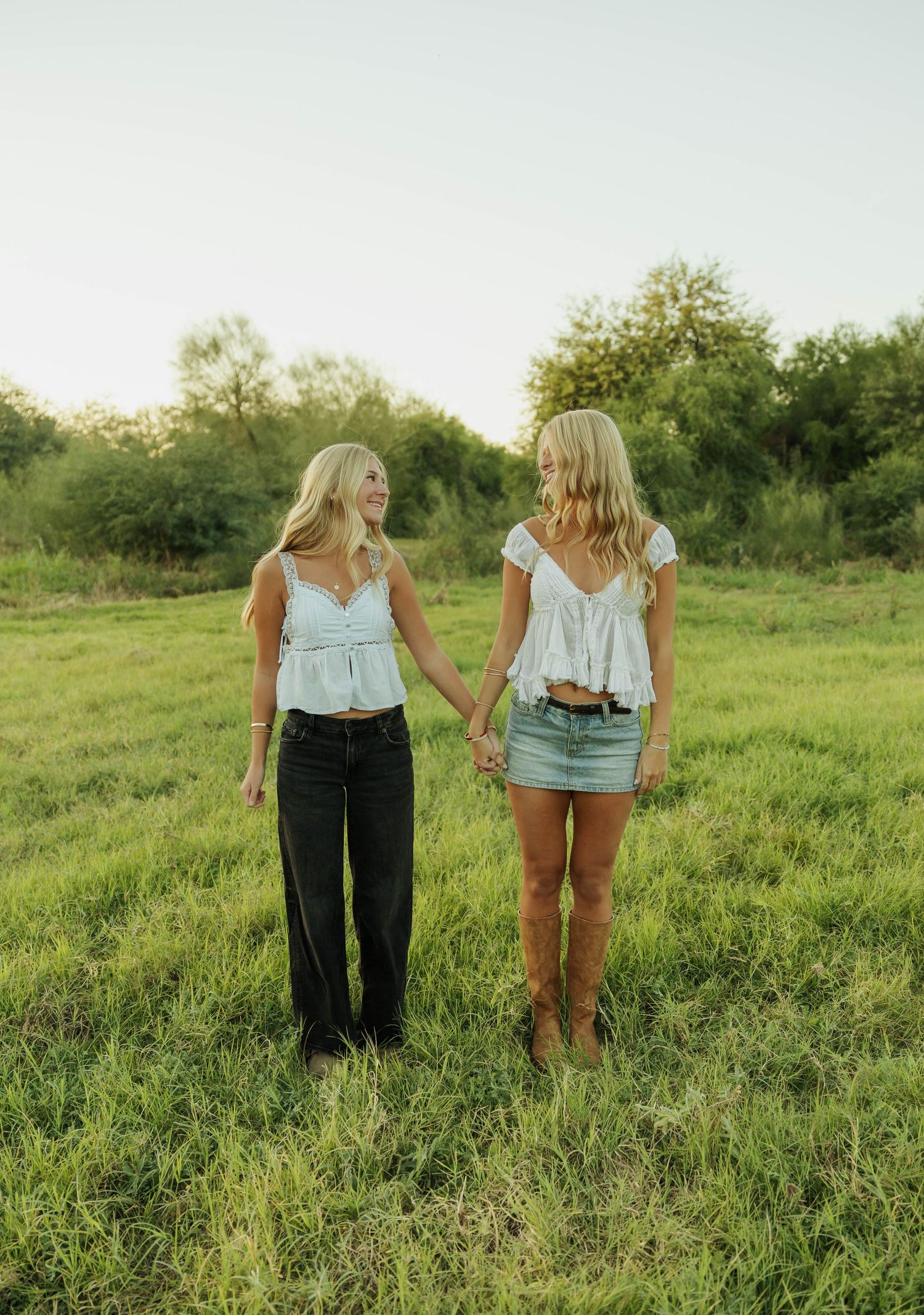 Two people walk together through a lush green meadow on a sunny summer day.