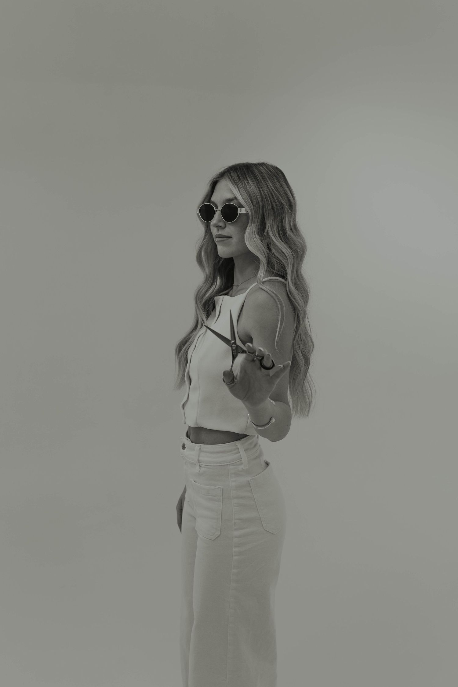 Black and white portrait of a person in sunglasses and casual attire posing against a plain background.