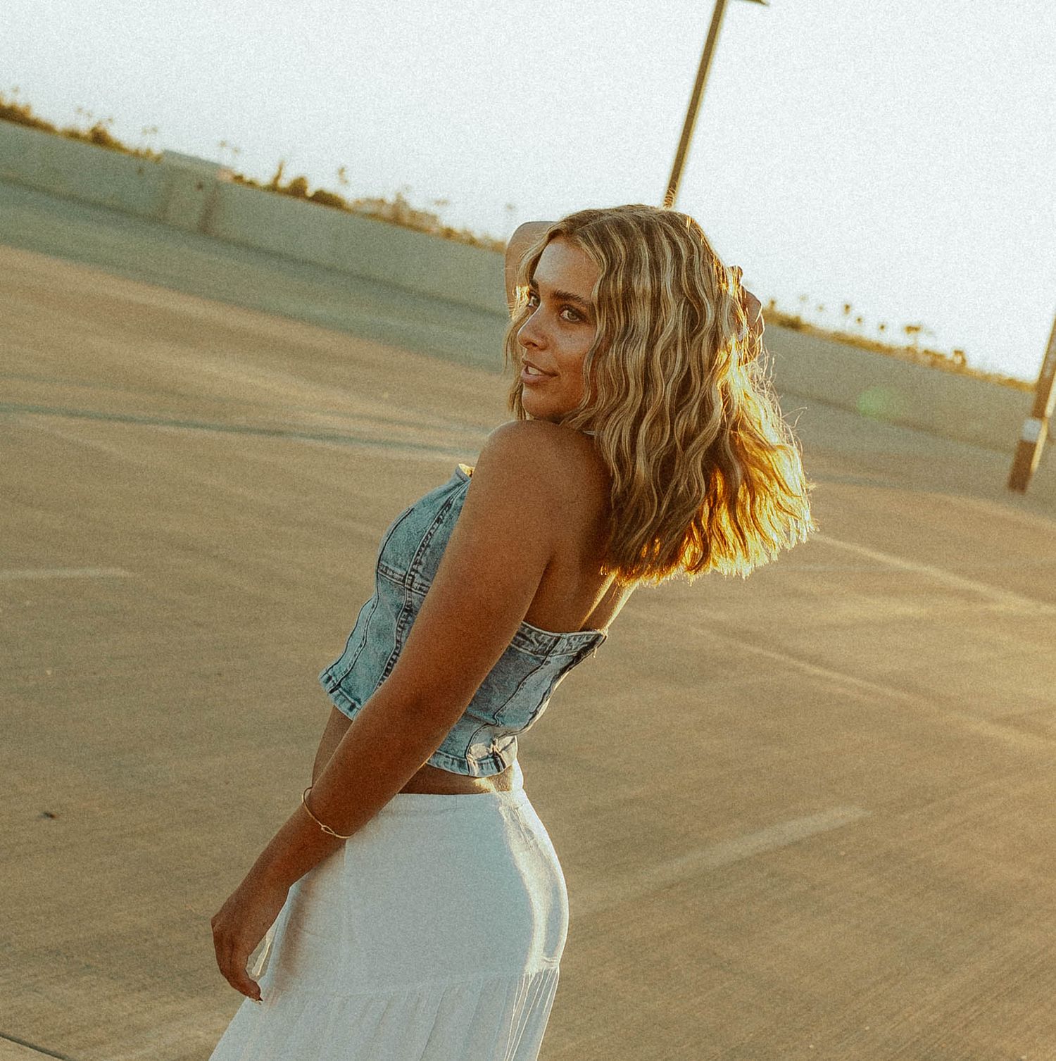 Senior cinematic photoshoot in denim and white clothing during sunset.