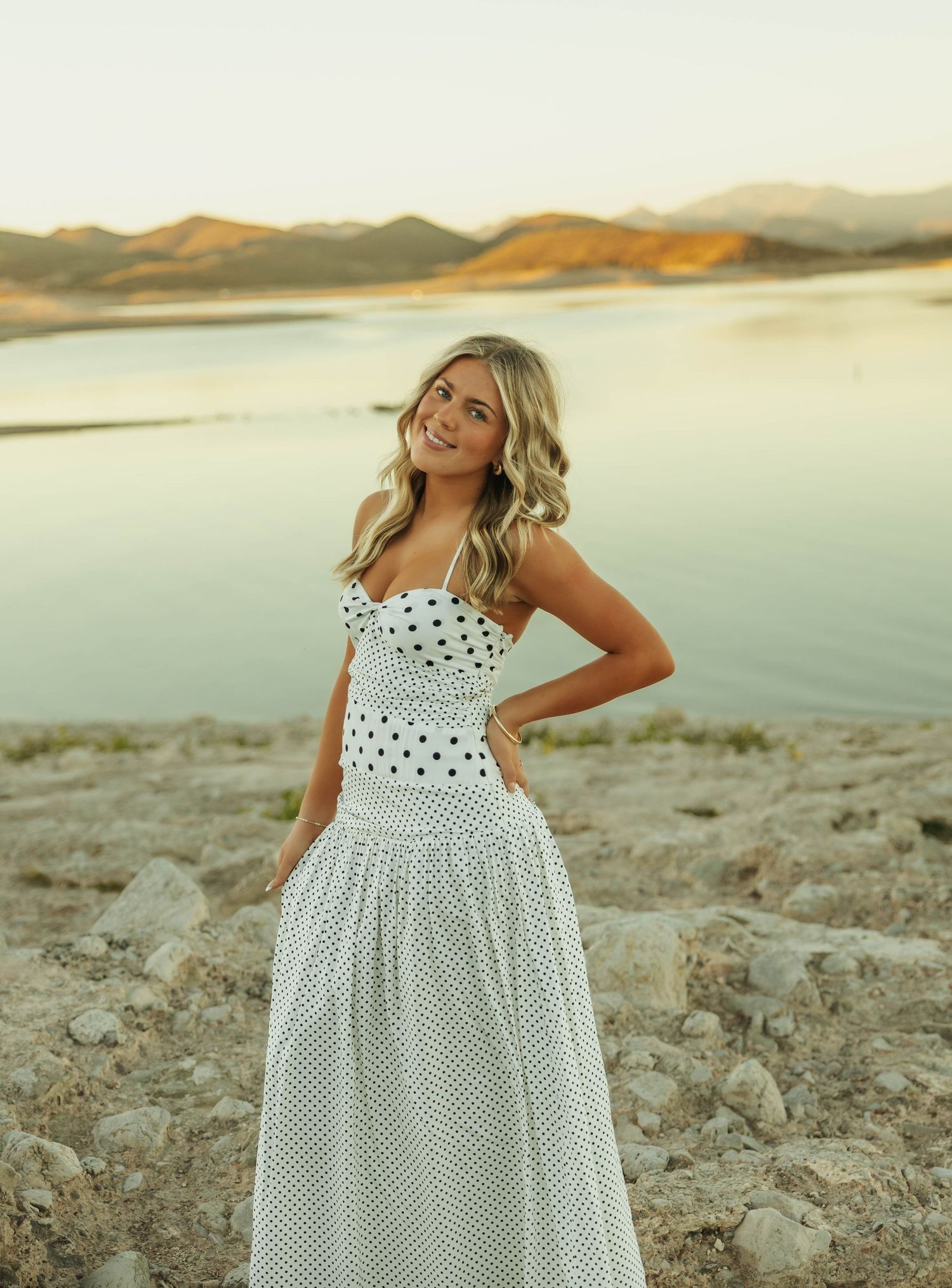 Polka dot sundress flows elegantly against lakeside desert backdrop.