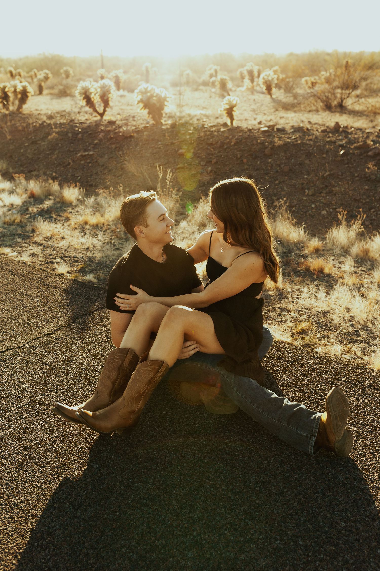 Couple shares intimate moment on desert ground during sunset.