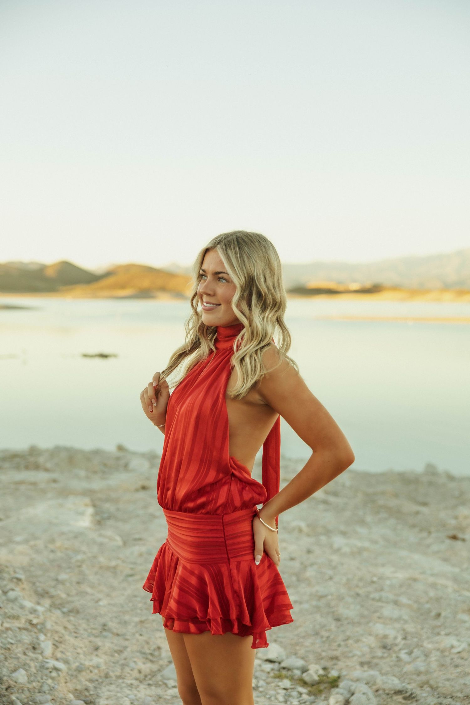 A red ruffled outfit photographed against a desert lake landscape.