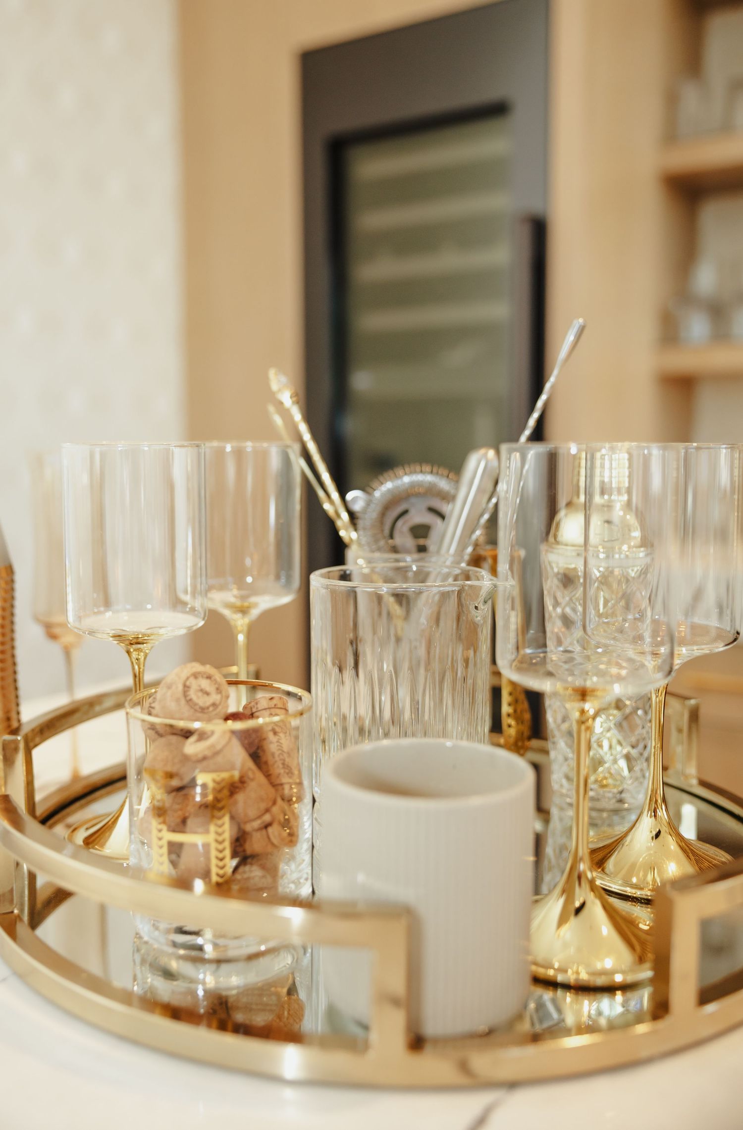 Elegant gold mirrored tray with crystal wine glasses, candle holders and decorative accessories in a luxurious home setting.