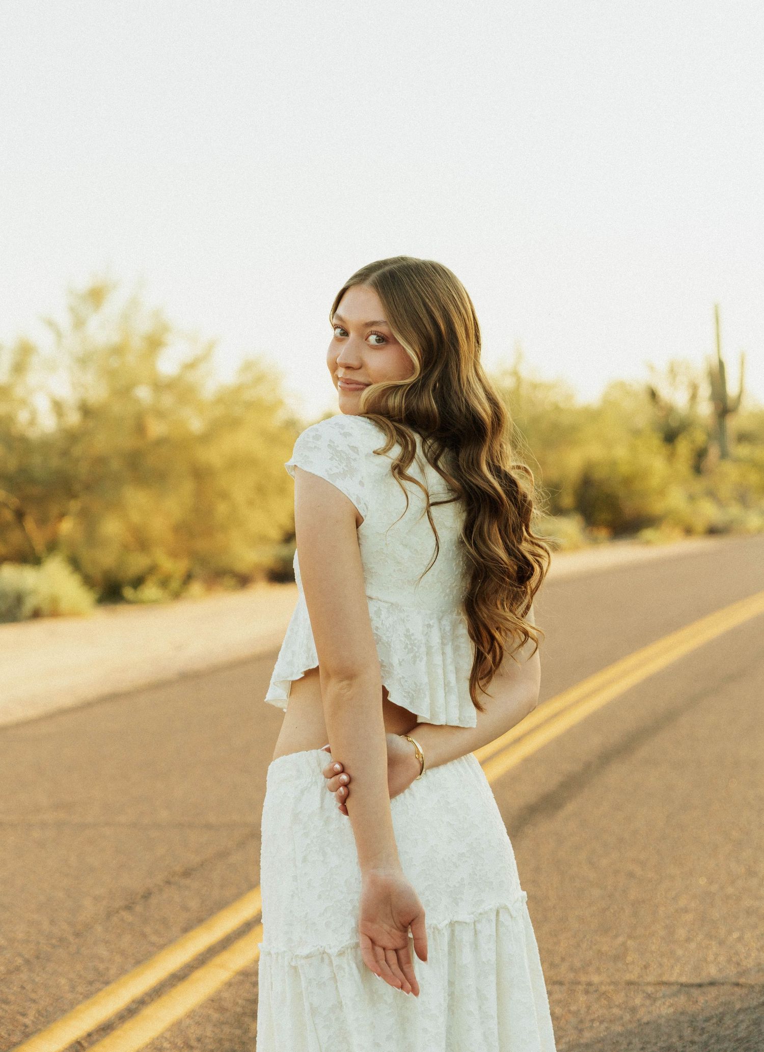 A white lace dress photographed in a desert setting with saguaro cacti at golden hour.