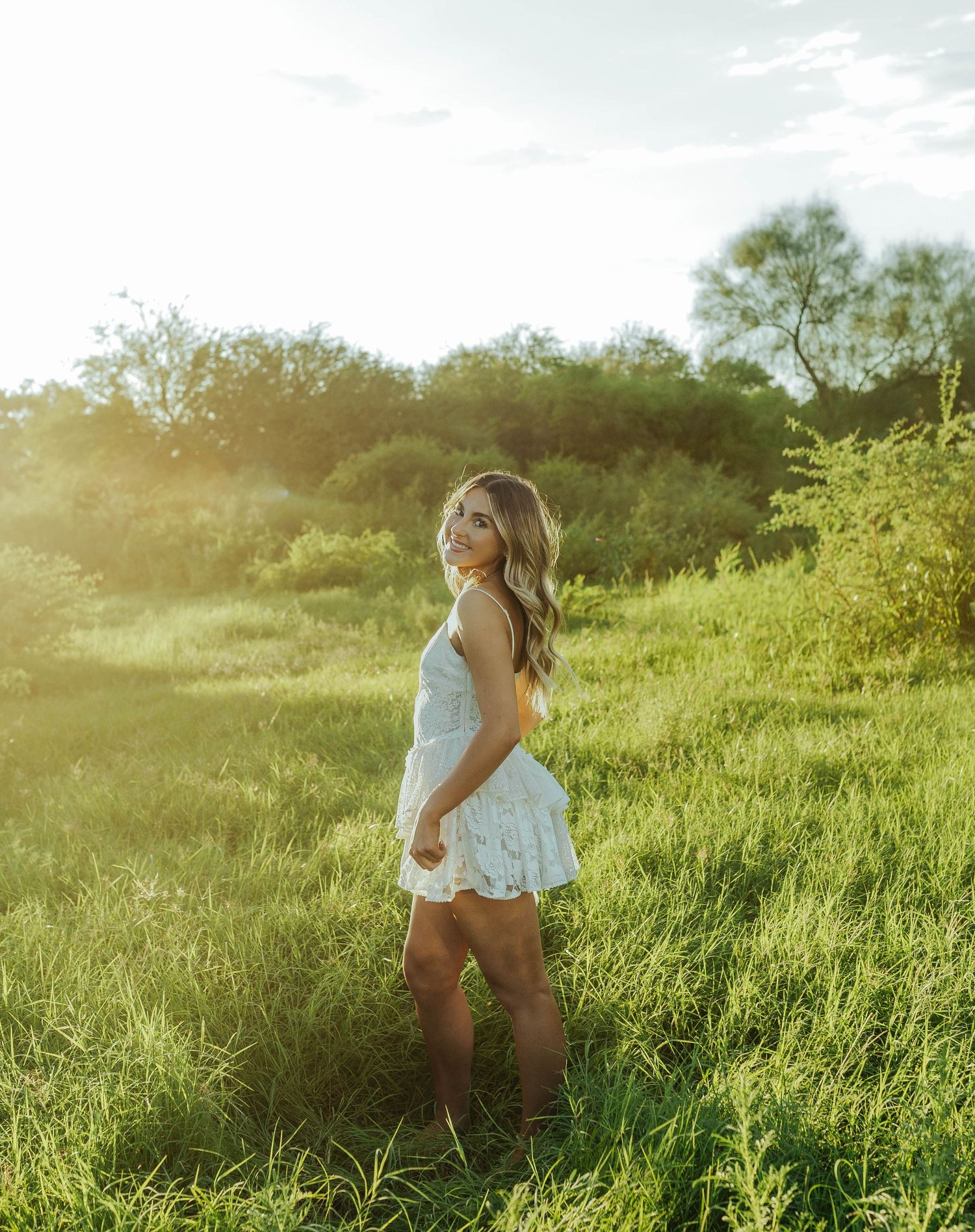 Person walking through a sunlit meadow with tall grass during golden hour.