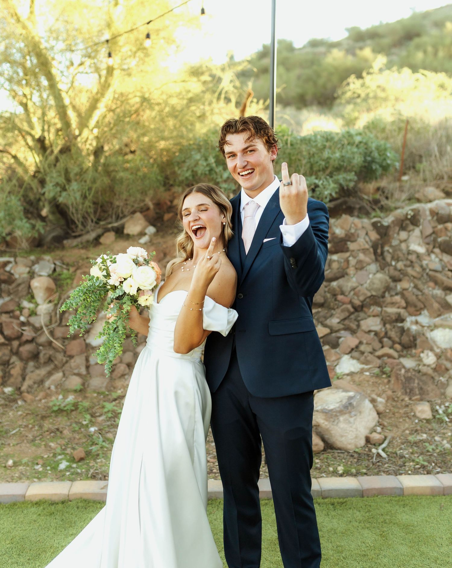 Newlyweds share joyful laughter during their outdoor wedding photoshoot.
