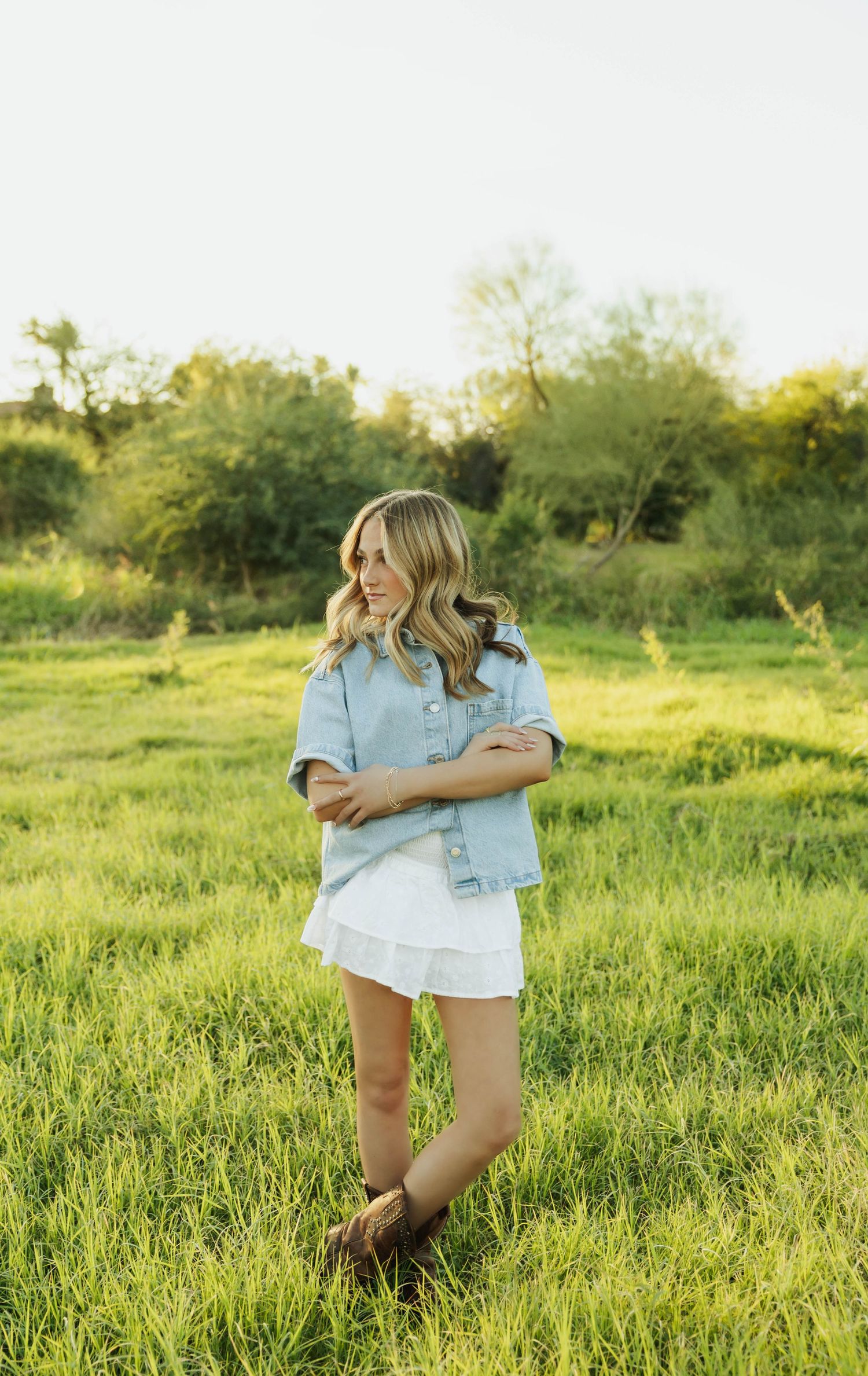Dancing and twirling in casual denim outfit on green grass field.