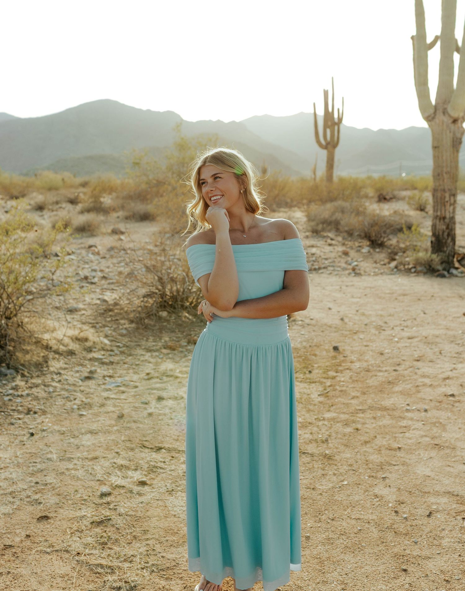 An off-shoulder turquoise dress captured in a desert landscape at sunset.