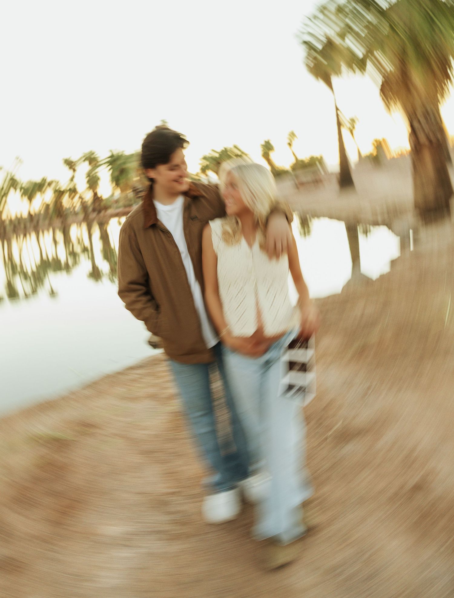 Motion-blurred sequence of a couple dancing together on a wooden floor with palm trees in the background at sunset.