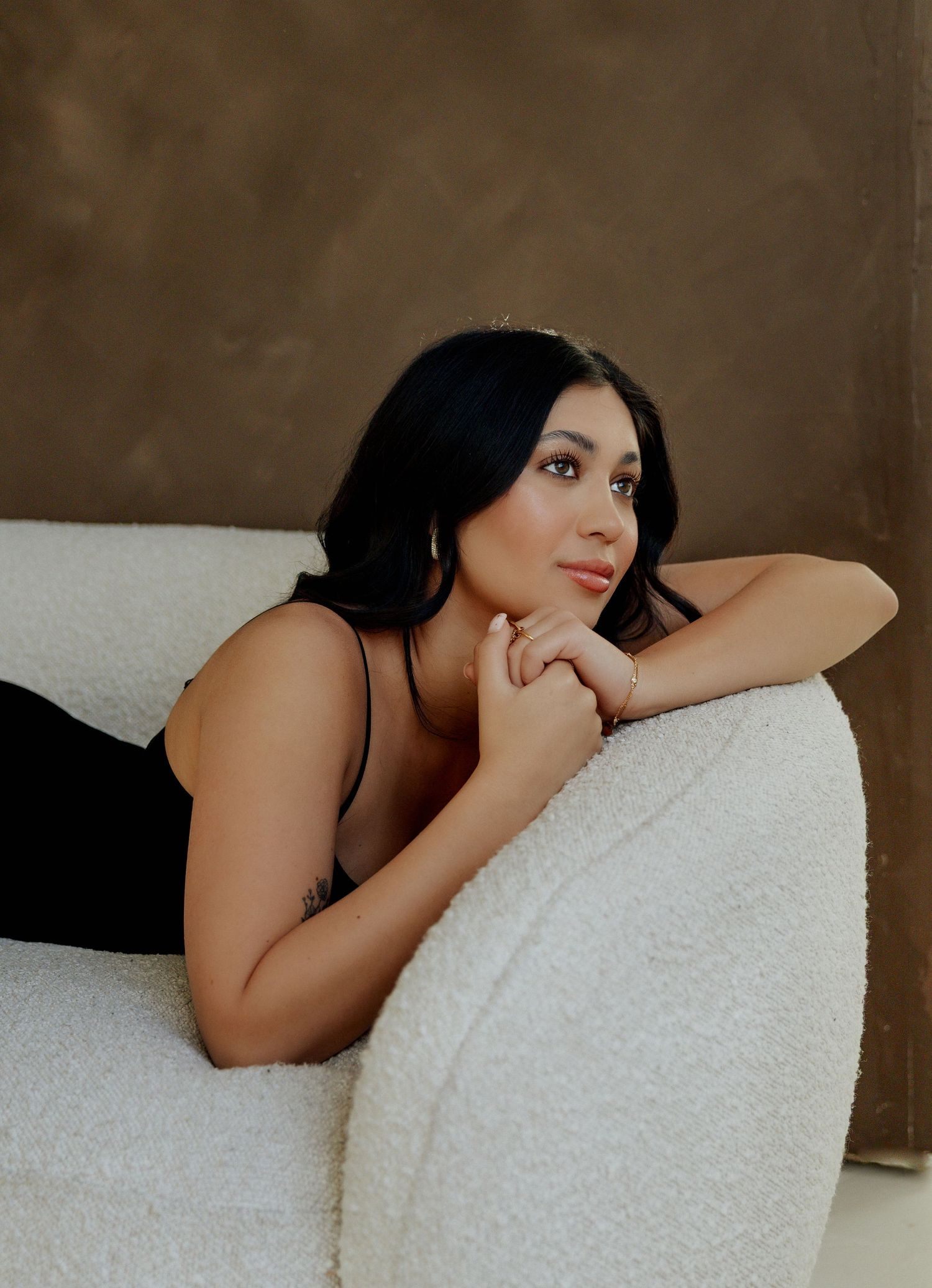 A series of artistic boudoir portraits showing a woman resting on white bedding in moody lighting.