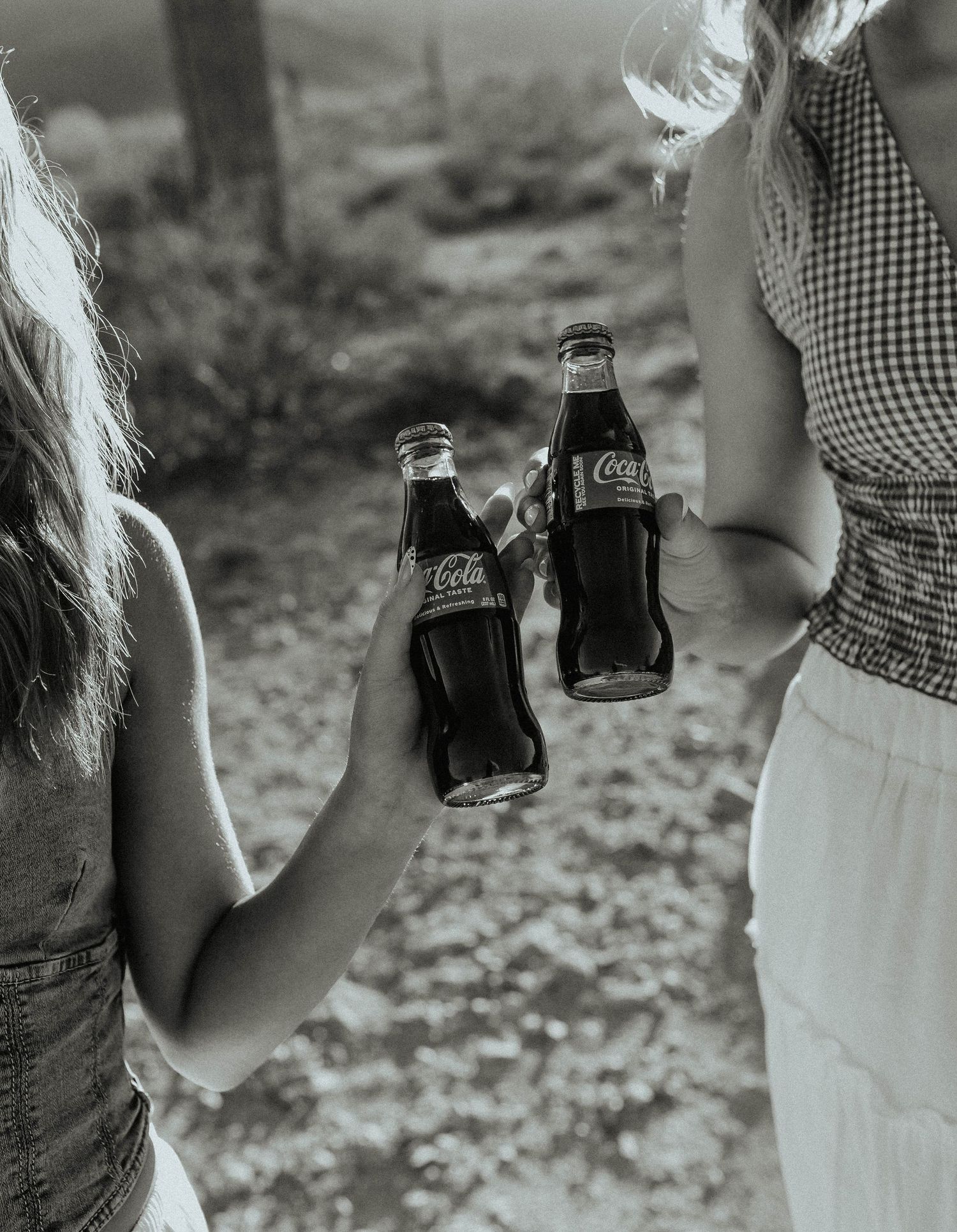 Black and white photo series showing someone holding a vintage Coca-Cola bottle in a natural outdoor setting.