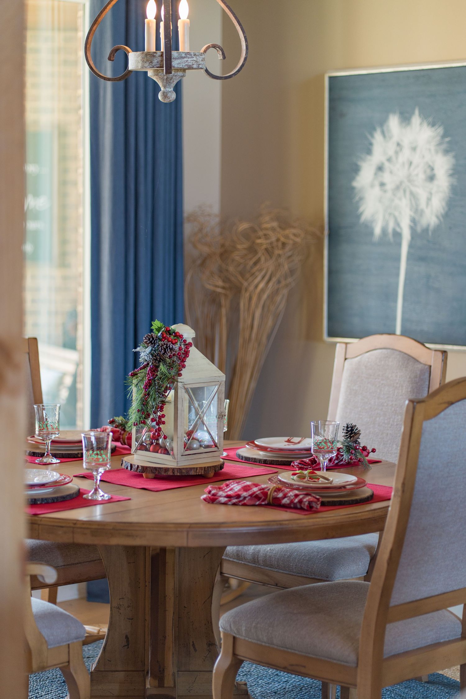 Elegant holiday dining table with red placemats, lantern centerpiece, and festive berry decor in a warm wooden setting.