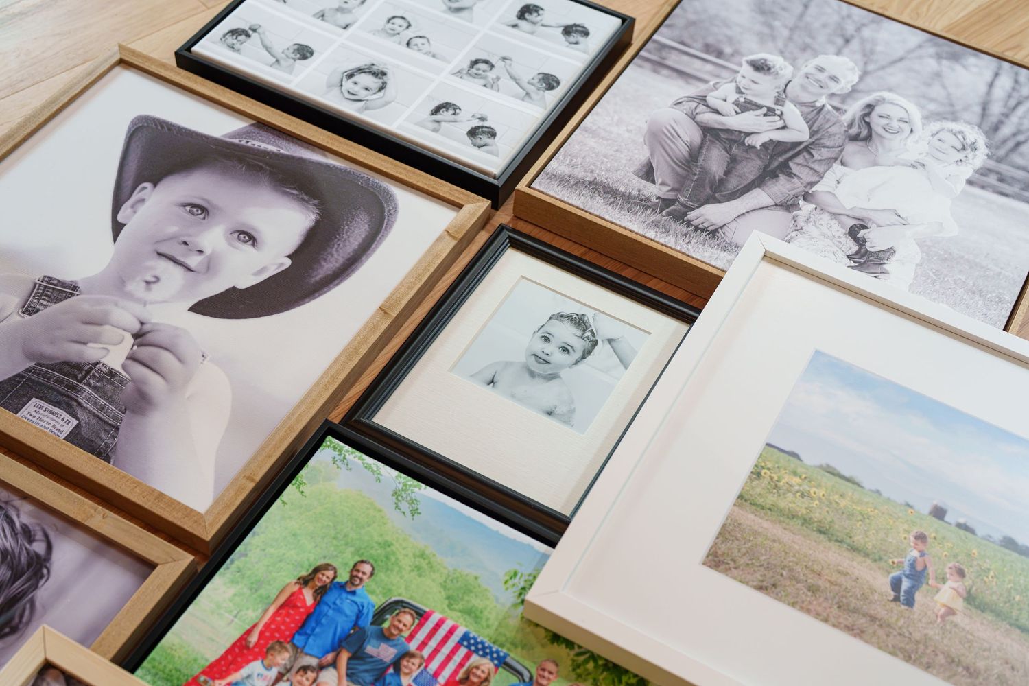 Collection of framed family photos and portraits in black-and-white and color, displayed on a wooden surface.