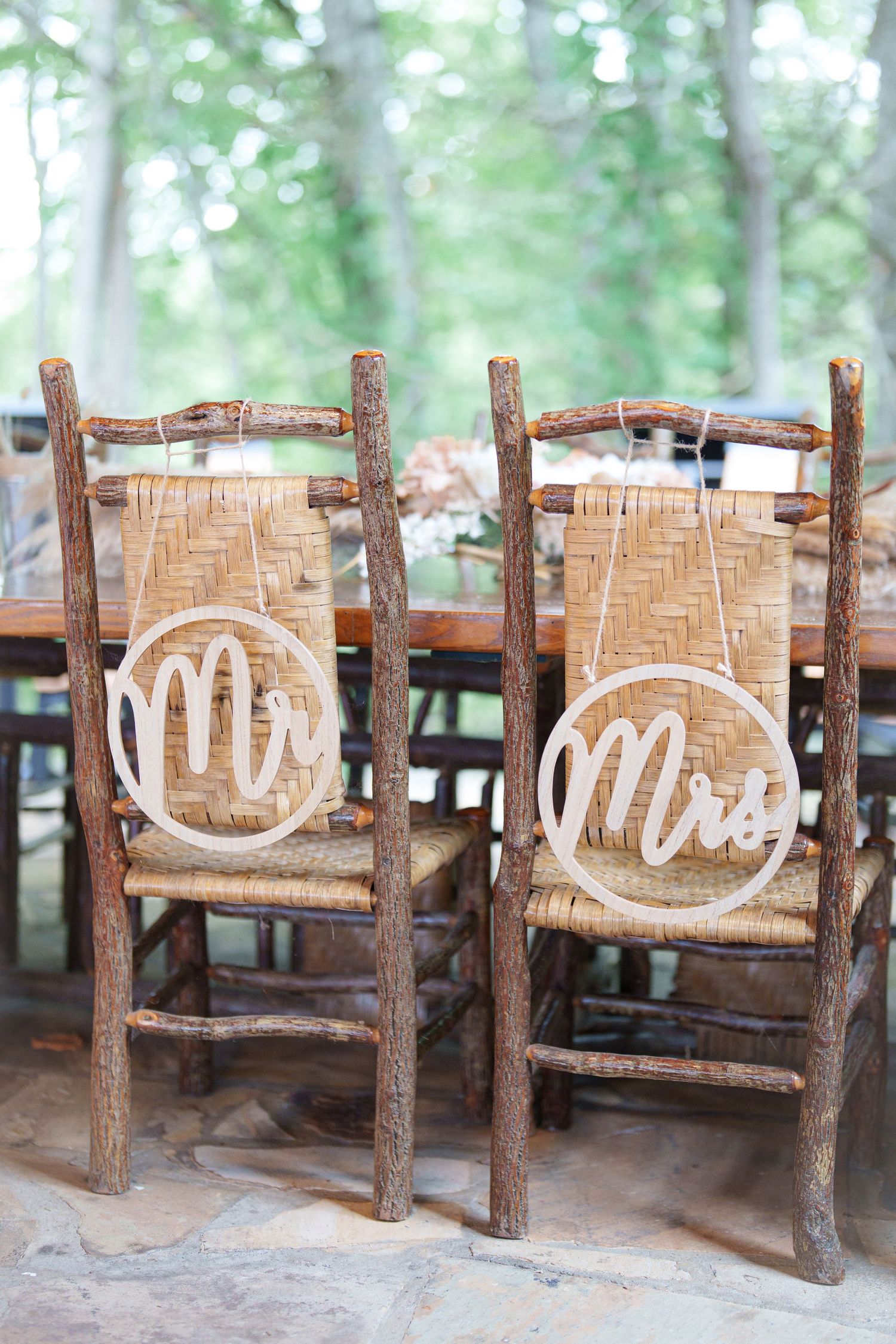Rustic wooden Mr. and Mrs. chair signs hanging on twig chairs at an outdoor wedding reception at the Roosevelt Lodge in Gatlinburg, TN.