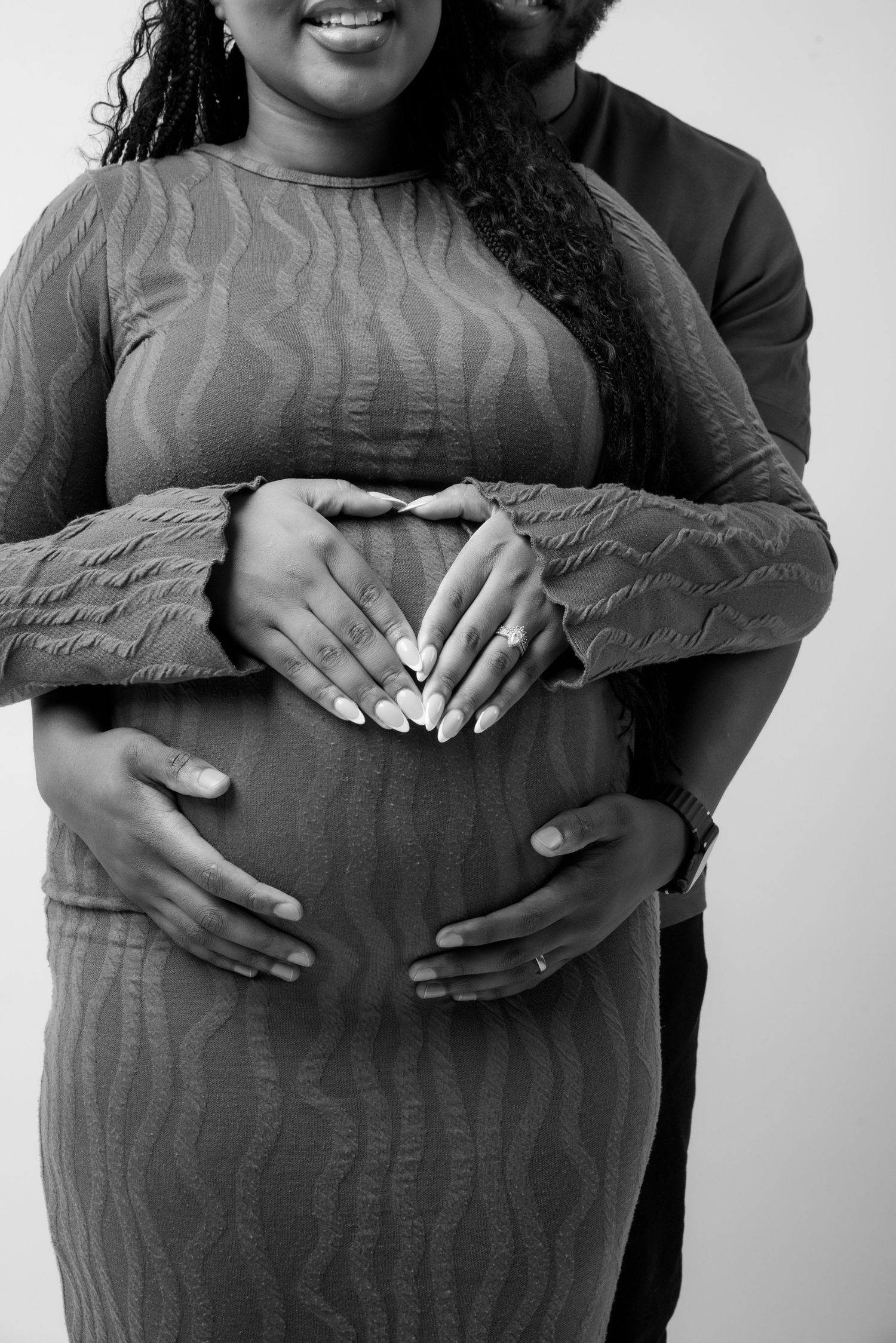 A series of black and white pregnancy photos showing hands lovingly cradling a growing baby bump.